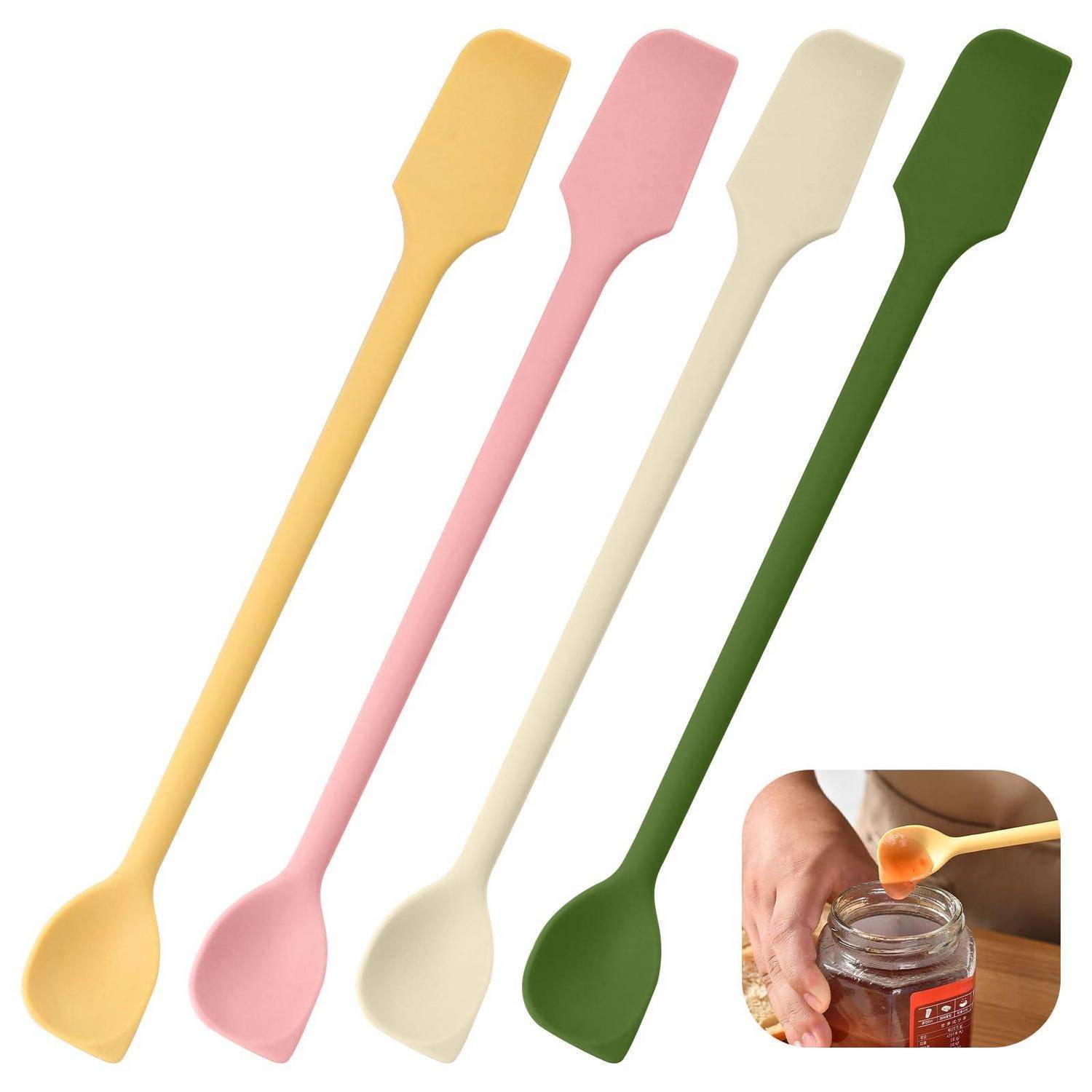 Vier langstieliges Silikonspachtel in Gelb, Rosa, Creme und Grün, mit einer kleinen Vergrößerung, die zeigt, wie einer Honig aus einem Glas schöpft.