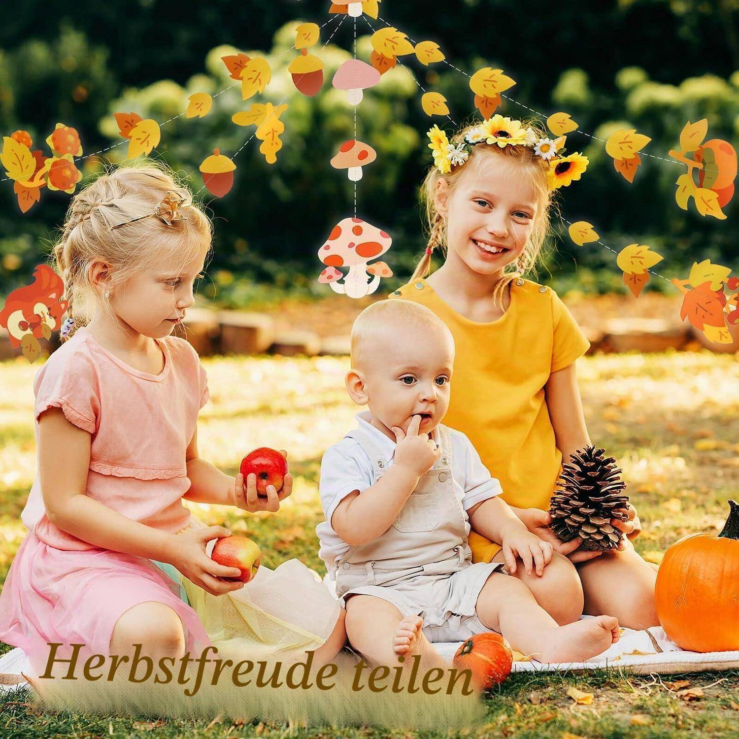 Drei Kinder sitzen im Herbst auf einer Decke im Freien, teilen Äpfel und einen Tannenzapfen, mit Herbstblättern und dem Text „Herbstfreude teilen".