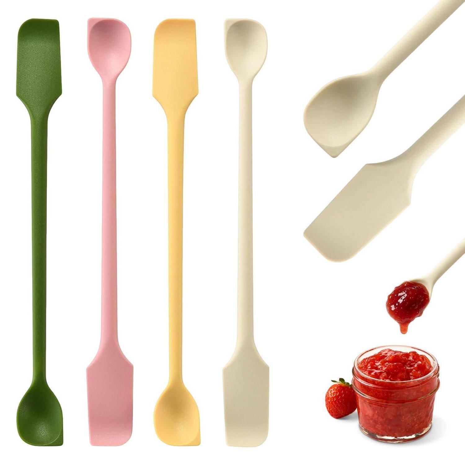 Sortierte Silikonspachtel in Grün, Rosa, Gelb und Creme, gezeigt mit cremefarbenen Utensilien, die Erdbeermarmelade aus einem Glas schöpfen.