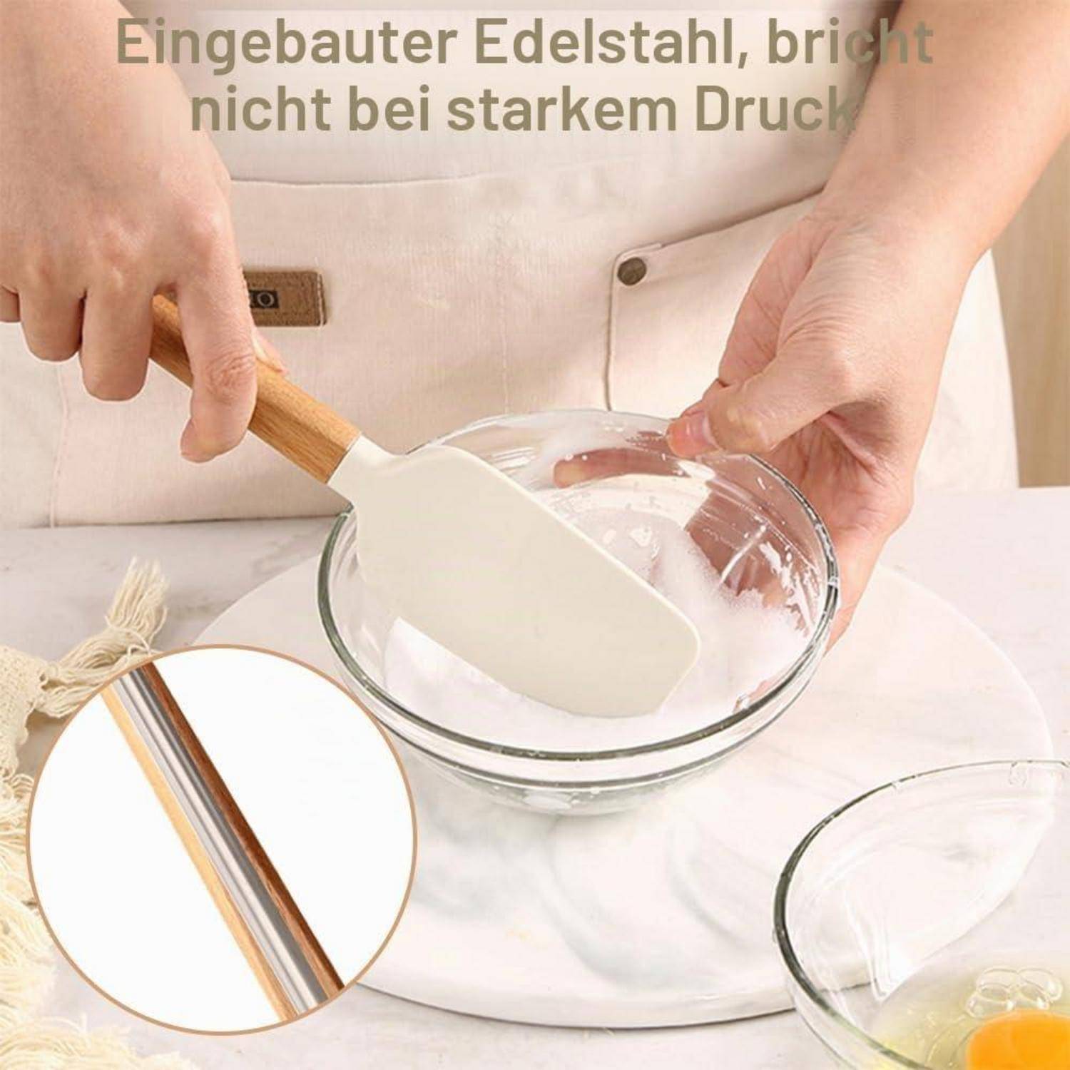Person rührt weiße Mischung in einer Glasschüssel mit einem Silikonspatel um; eine Vergrößerung zeigt den Edelstahlkern, mit deutschem Text, der besagt „eingebauter Edelstahl, nicht unter starkem Druck