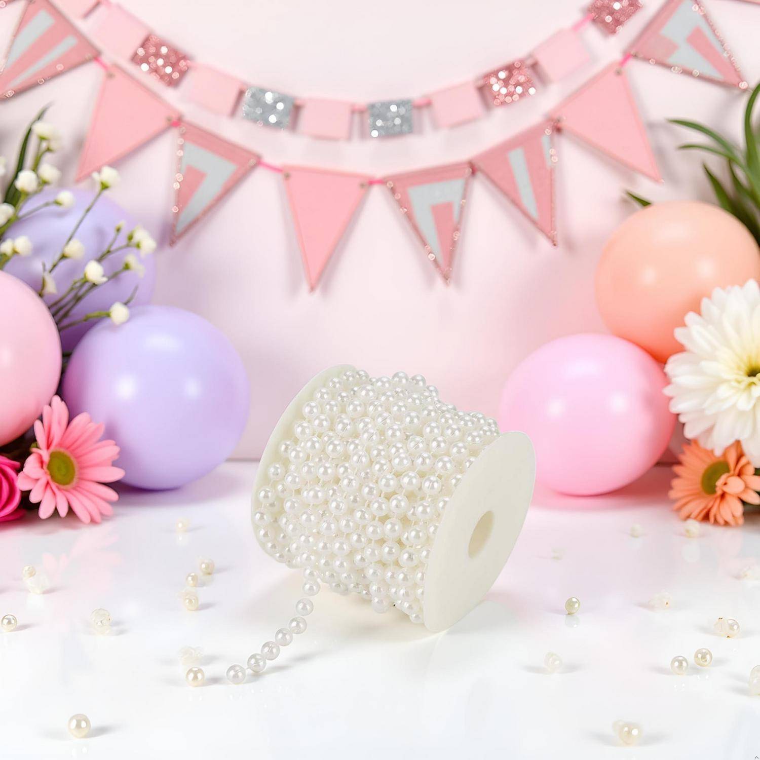 Perlenschpule auf einem pastellfarbenen Partyhintergrund mit rosa Girlanden, Luftballons und Blumen.