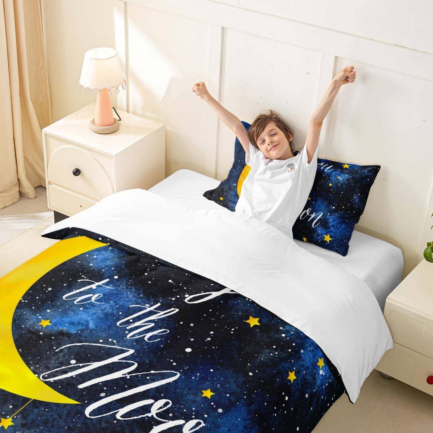 Lachendes Kind, das sich im Bett streckt, mit weltraumbezogenen Bettwäsche und Sternen-Kissen in einem hellen Schlafzimmer