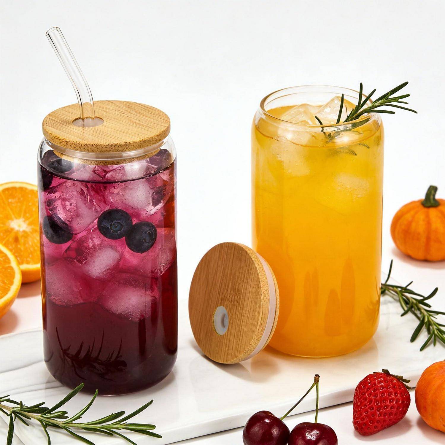 Zwei gekühlte Fruchtgetränke in Glaskrügen mit Bambusdeckeln und Strohhalmen: ein violettes Beerengetränk und ein gelbes Zitrusgetränk, garniert mit Rosmarin und Fruchtscheiben.