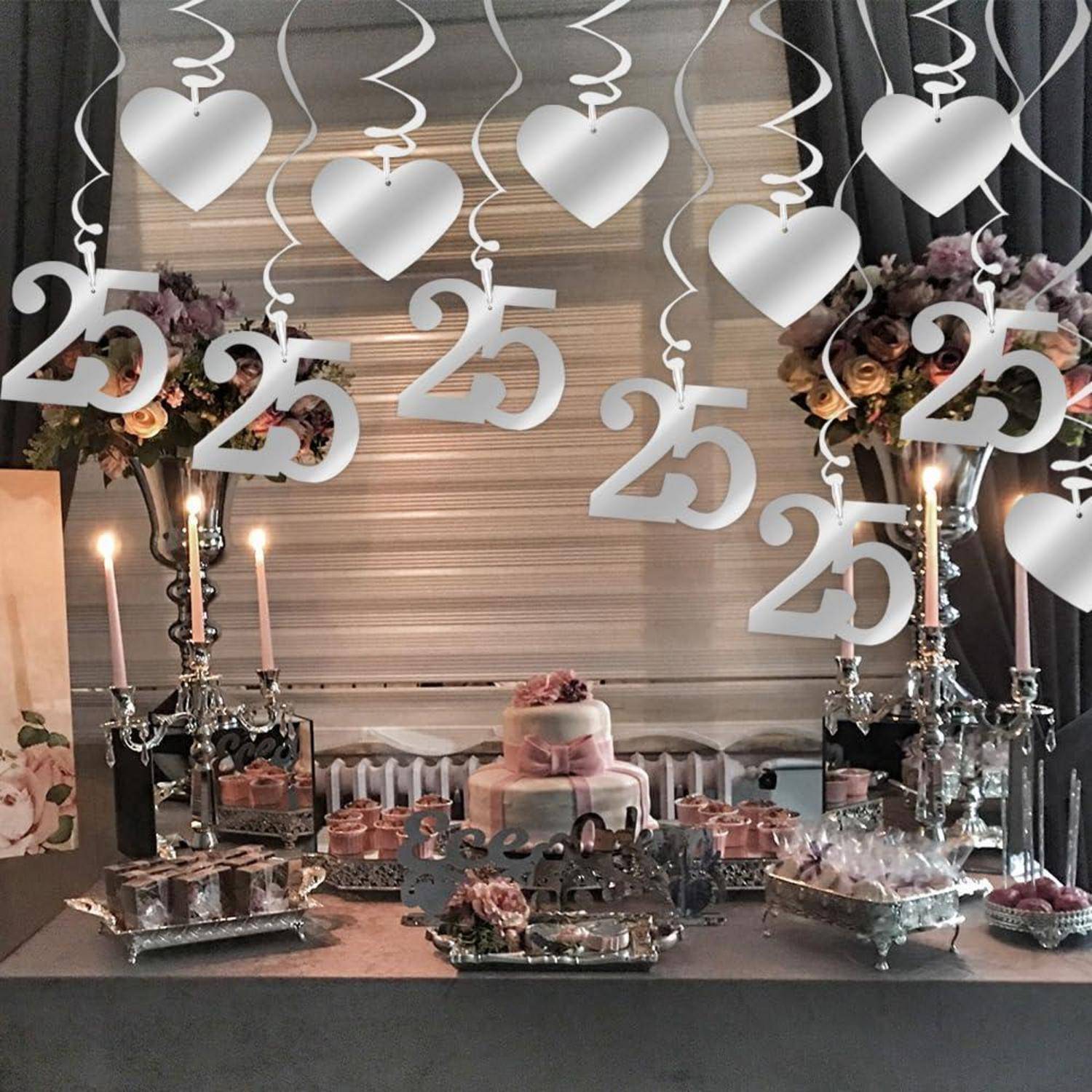 Dekorierter Dessert-Tisch zum 25. Jahrestag mit weißen Herz- und „25"-Hängdekorationen, Kerzen, Blumenarrangements und einer mehrstöckigen Torte.