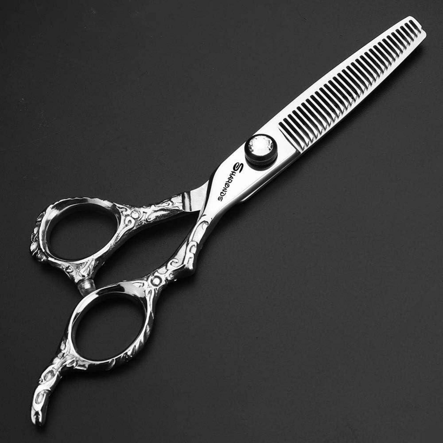 Silberne Haarschneidescheren mit verziertem Fingerauflage und gezackter Klinge auf dunklem Hintergrund.