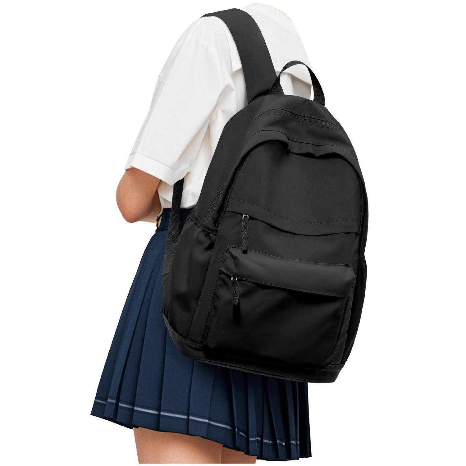 Person in Schuluniform trägt einen großen schwarzen Rucksack auf dem Rücken vor weißem Hintergrund.
