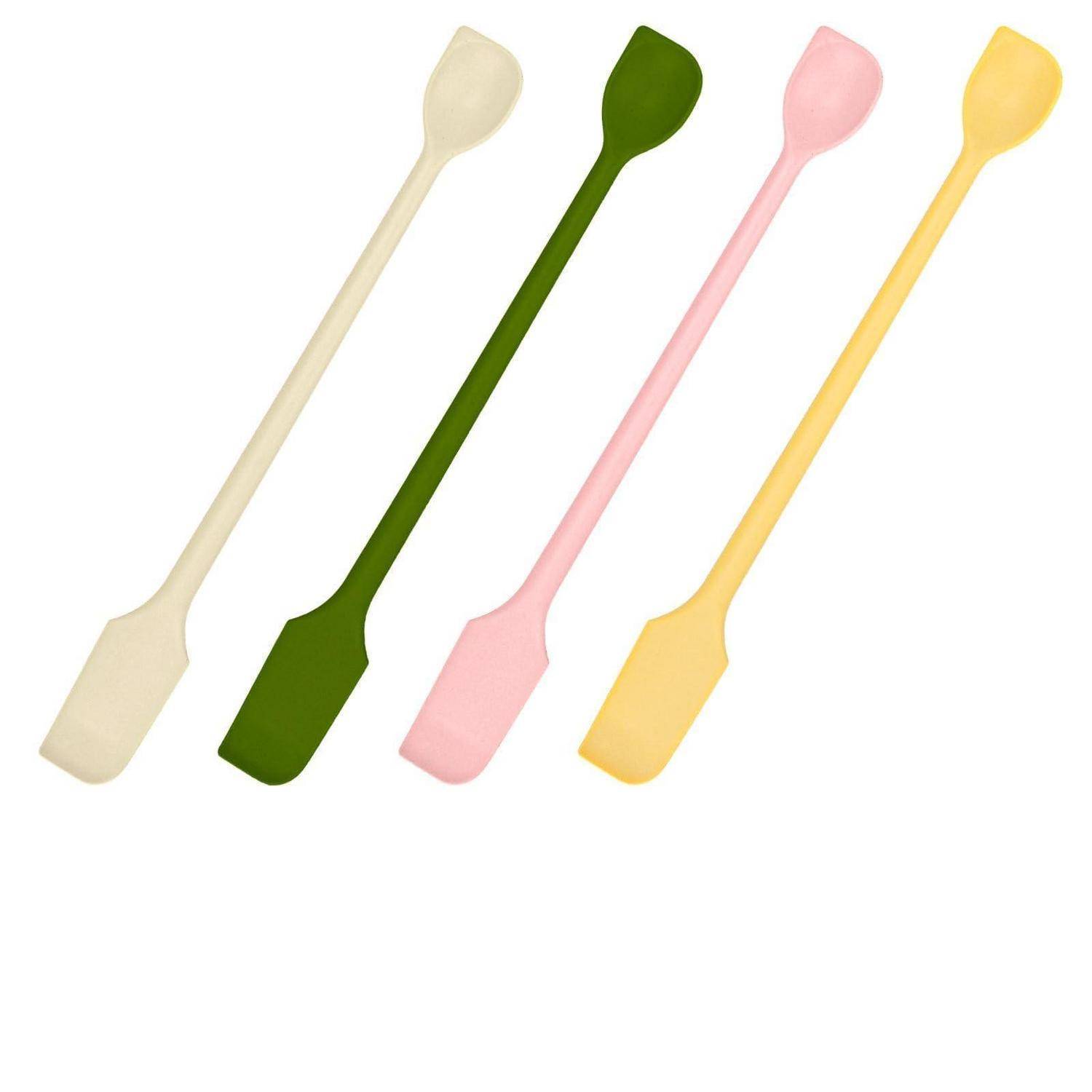 Vier farbenfrohe doppelseitige Spatel oder Rührstäbe in Creme, Grün, Rosa und Gelb auf weißem Hintergrund.