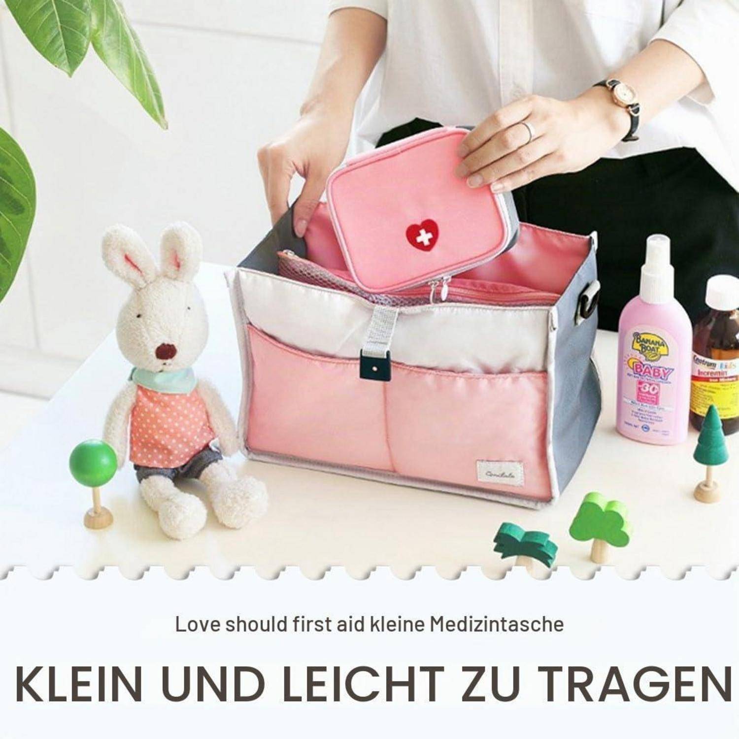 Rosa Erste-Hilfe-Tasche mit einem kleinen passenden Koffer und Medizinflaschen neben einem Plüschhäschen; deutscher Text sagt "klein und leicht zu tragen"".