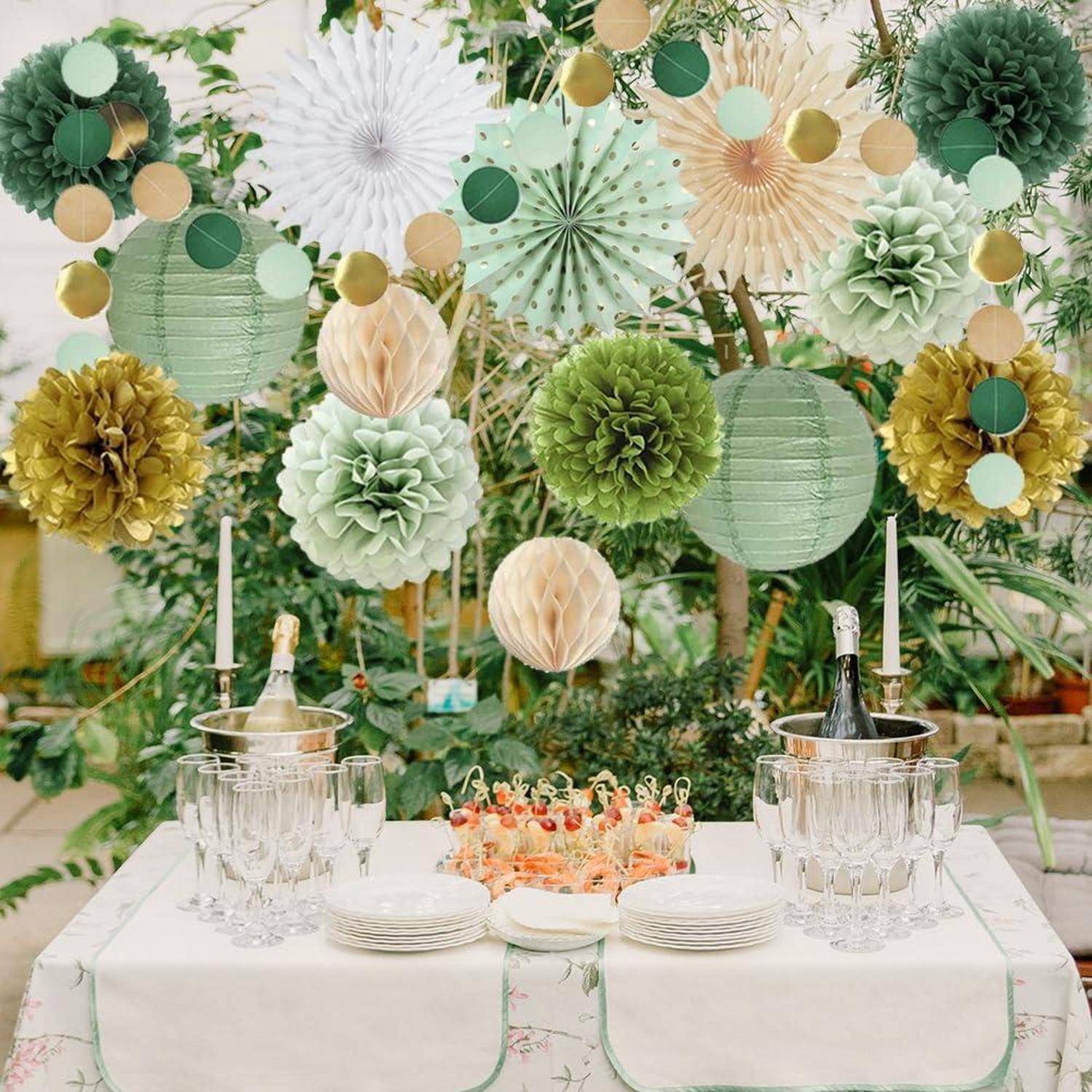 Dekorierter Partytisch mit Champagnerflaschen, Glaswaren, Tellern und blumigem Dessert, angeordnet vor einem grünen und cremefarbenen Papierblumen-Hintergrund.