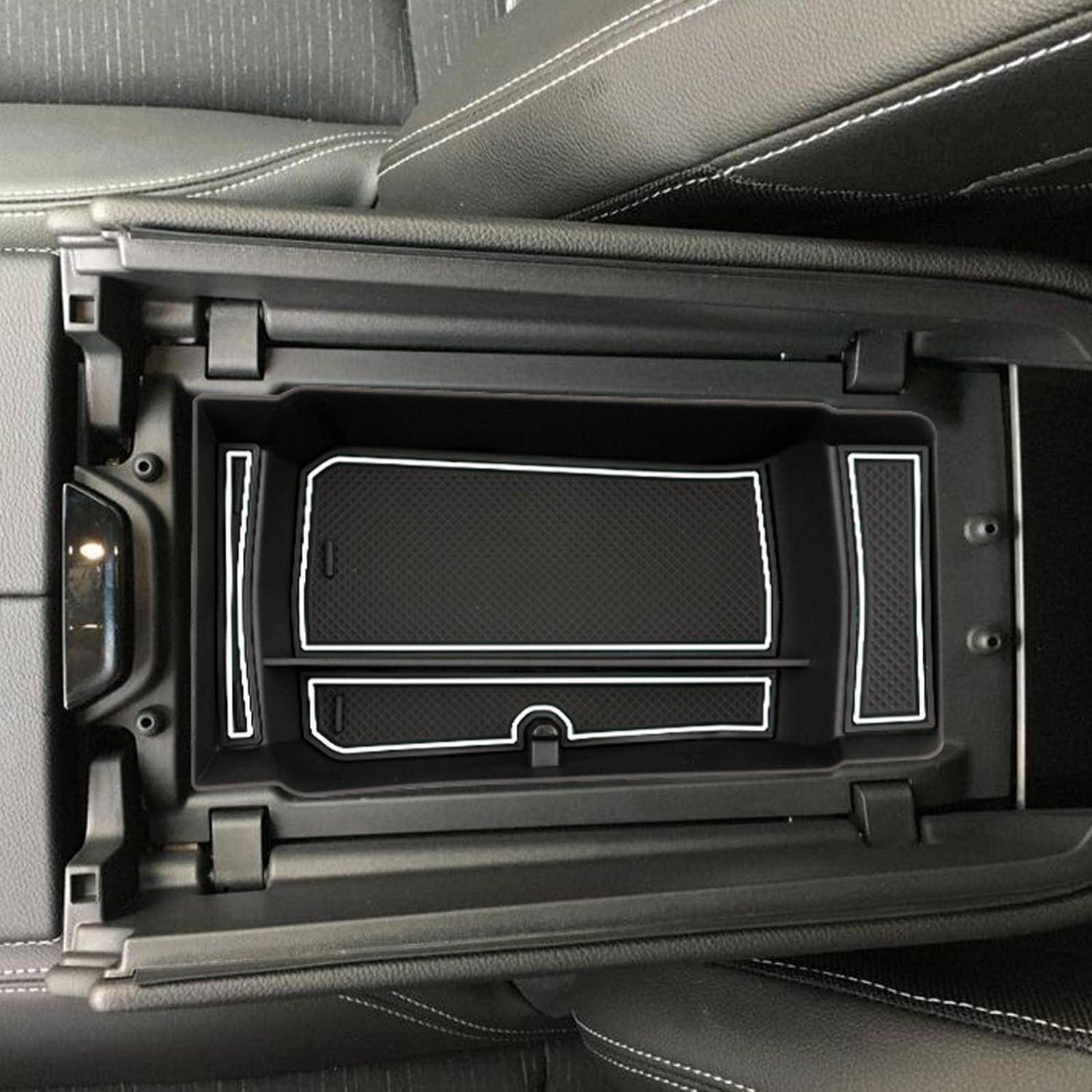 Offenes Mittelkonsolenstaufach in einem Auto, gezeigt mit einem geteilten Tablett und gepolstertem schwarzem Innenraum.