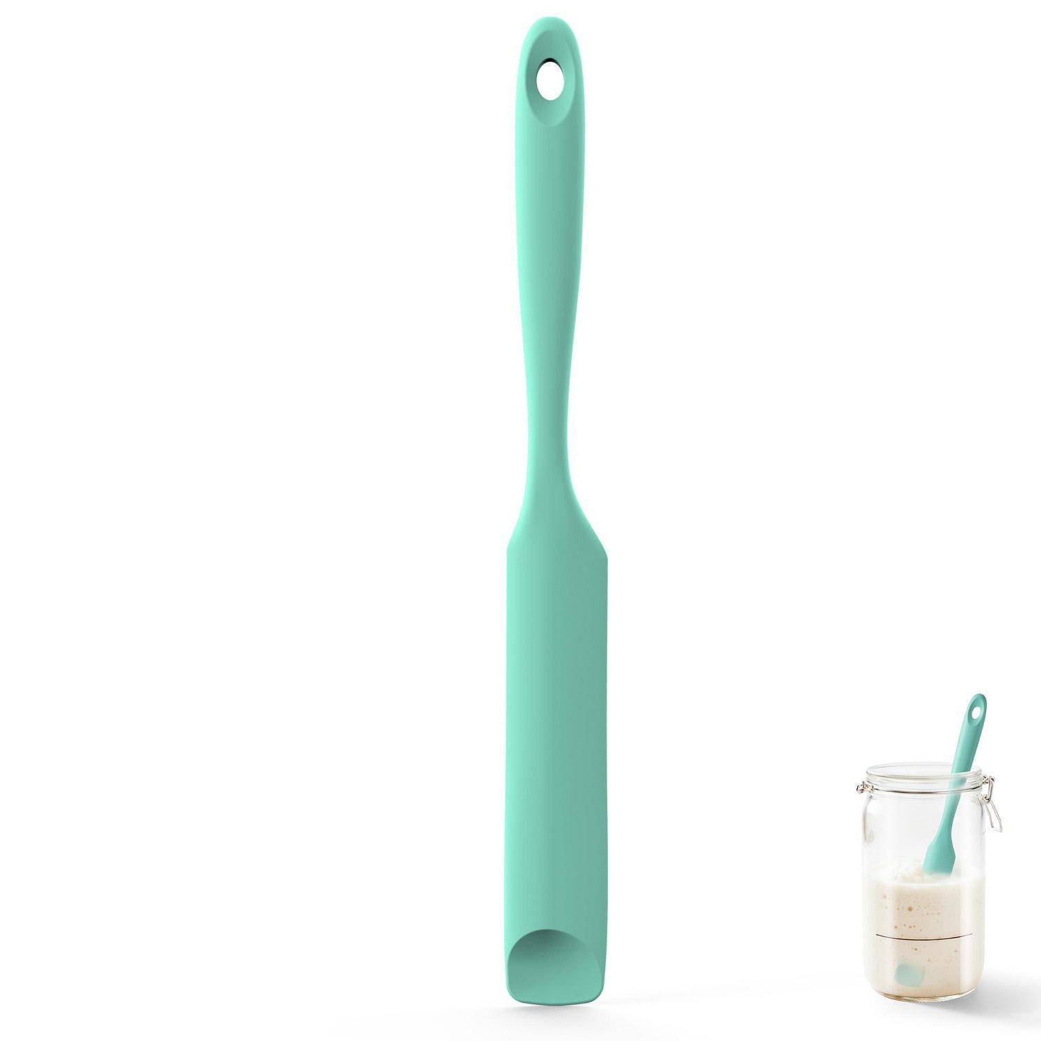 Minzgrüner Silikonspachtel mit Aufhängeloch und flacher Kante, neben einem Glas mit Teig oder Backteig gezeigt.