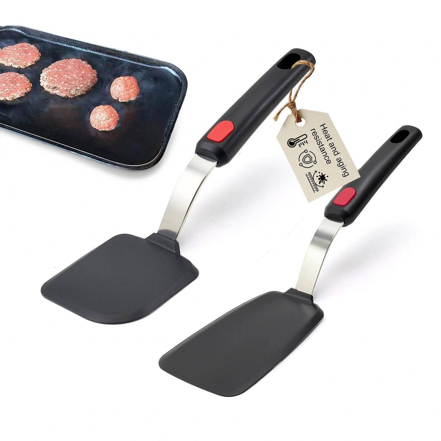 Zwei schwarze hitzebeständige Spatel mit roten Daumenknöpfen, gezeigt neben einer Grillplatte mit kochenden Burger-Patties.