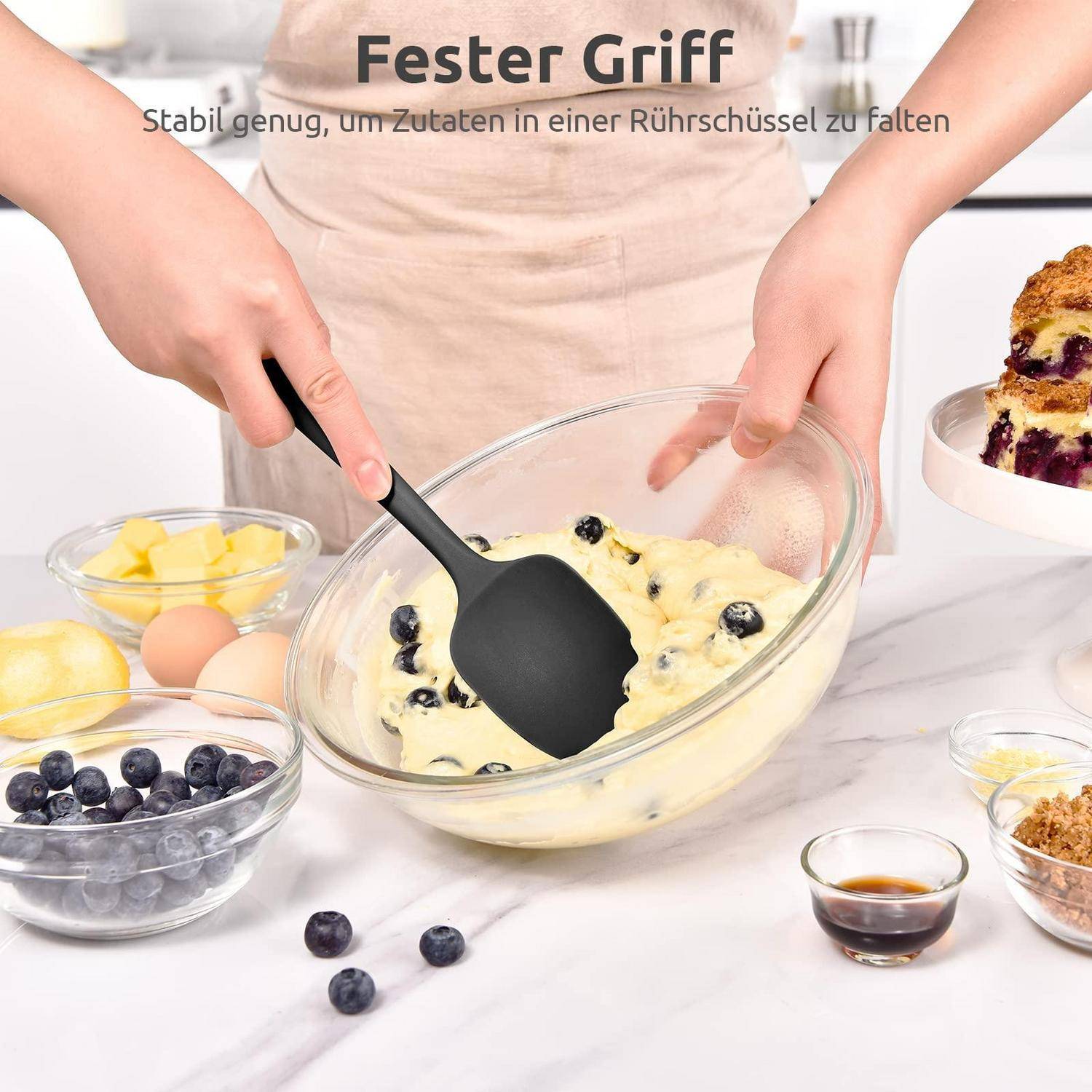 Hände, die Heidelbeerkuchen-Teig in einer Glasschüssel mit einem schwarzen Spatel mischen; deutscher Text liest sich „Besserer Griff