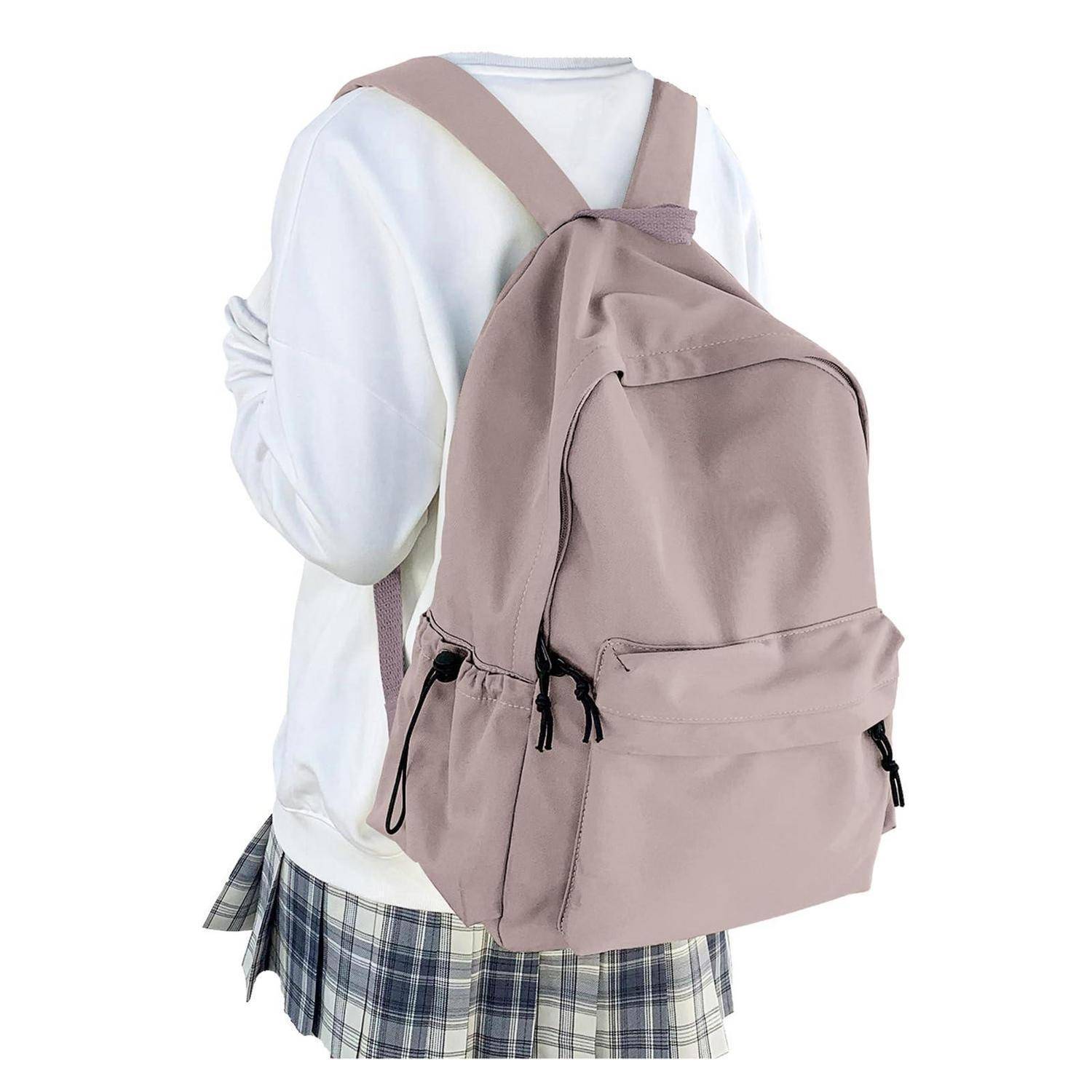 Person trägt einen hellrosa Rucksack über einem weißen Hemd und einem karierten Rock, von hinten vor einem einfarbigen Hintergrund gezeigt.