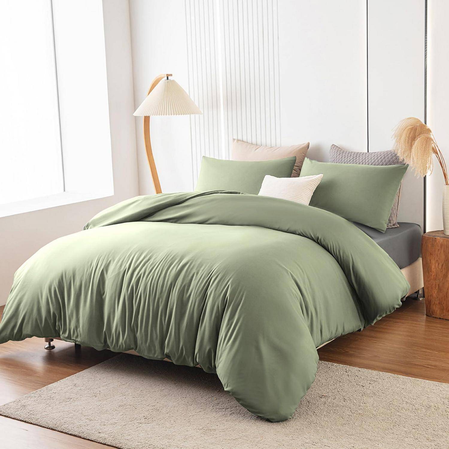 Modernes Bett mit hellgrüner Bettwäsche und Kissen in einem hellen minimalistischen Schlafzimmer, mit einer Stehleuchte, Holzakzenten und Teppich.