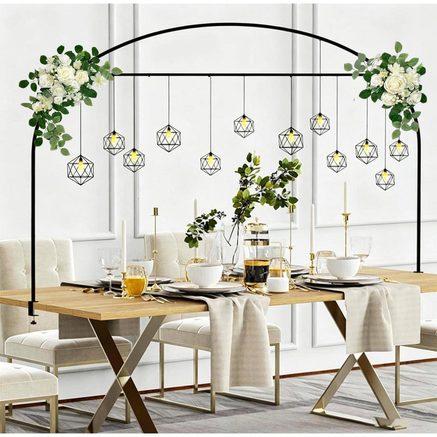 Elegante Tischdeckung unter einem schwarzen Bogen mit hängenden geometrischen Leuchten und weißem Blüten-Grünwerk in einem hellen modernen Esszimmer.