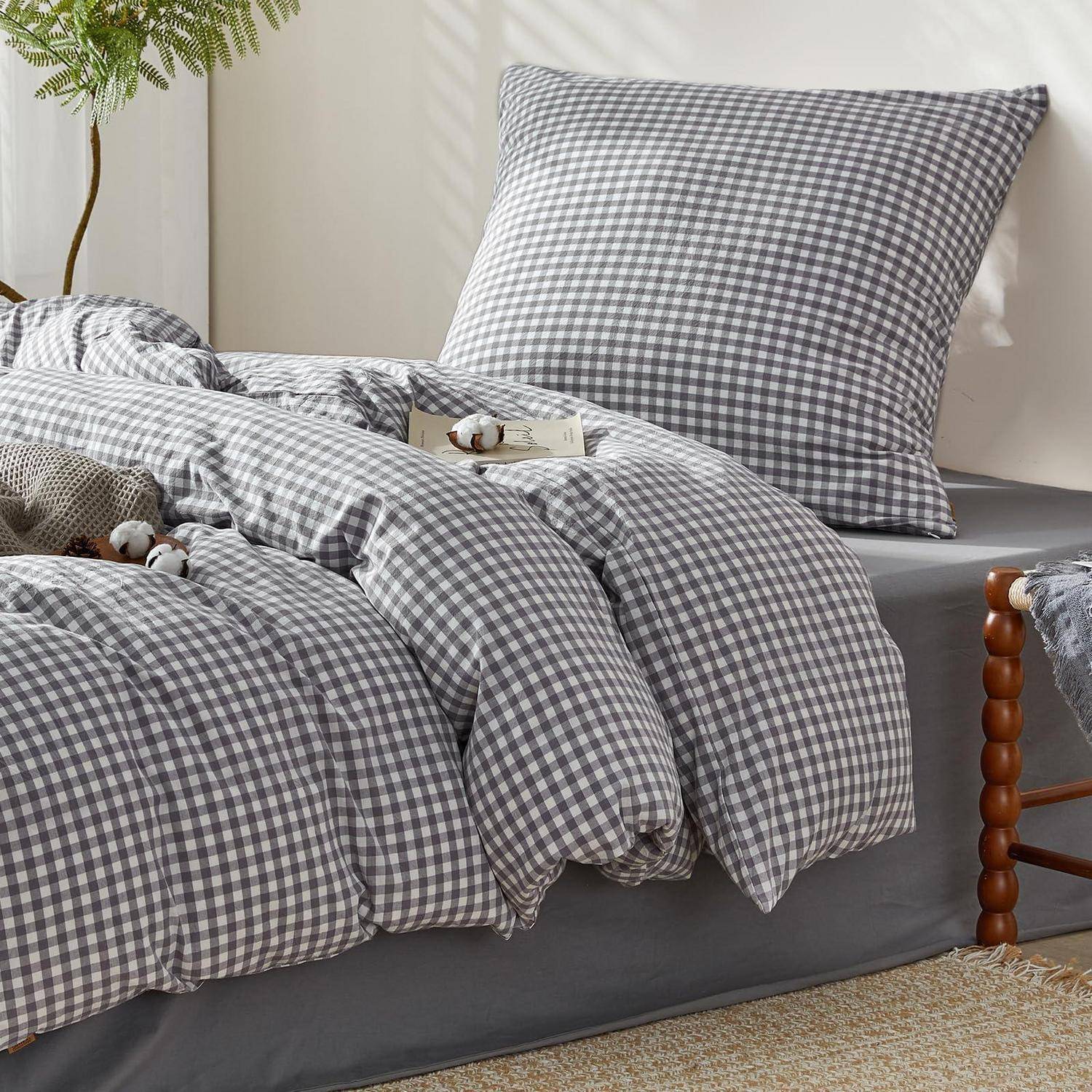 Grau kariertes Bettwäsche-Set mit Kissen und Bettdecke auf einem ordentlich gemachten Bett in einem hellen Schlafzimmer.