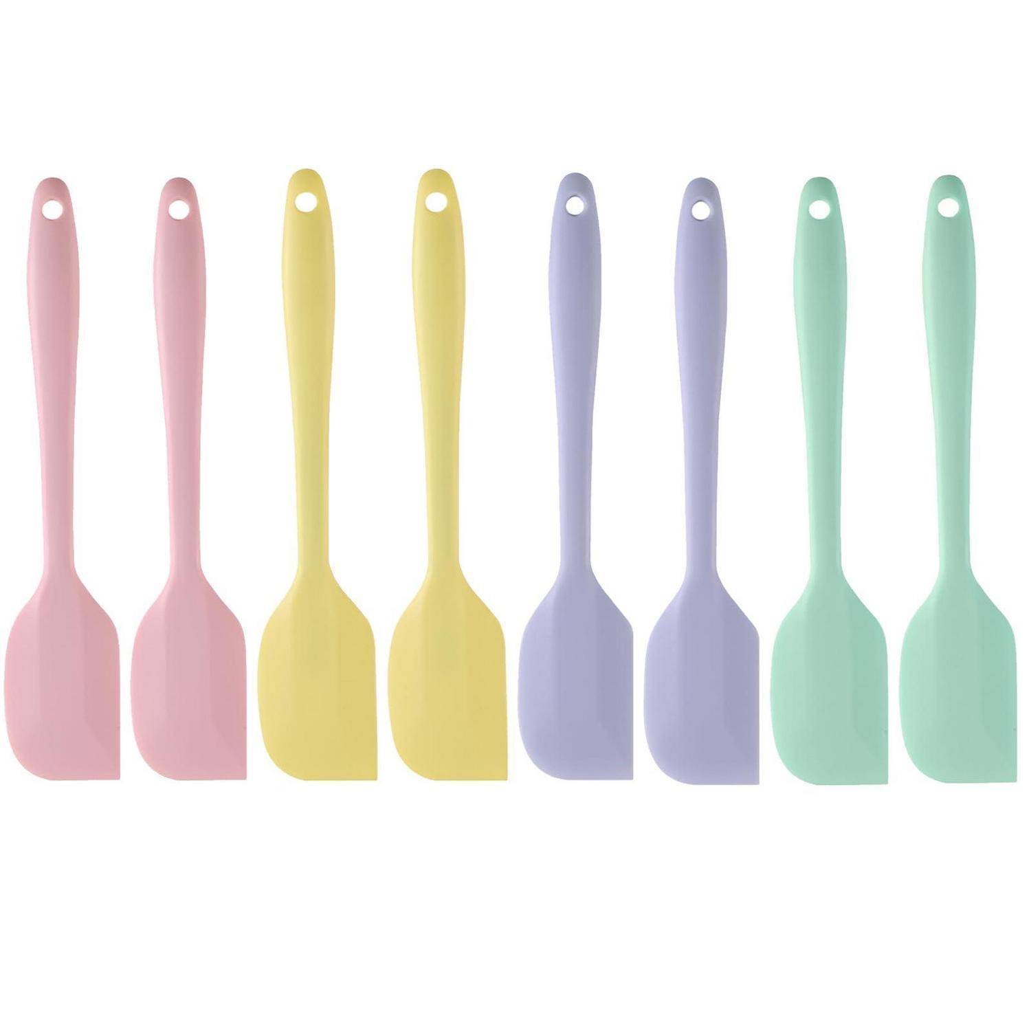 Acht pastellfarbene Silikon-Spatel oder Spoonula-Werkzeuge in einer Reihe auf weißem Hintergrund angeordnet: zwei rosa, zwei gelb, zwei lavendel und zwei mintgrün.