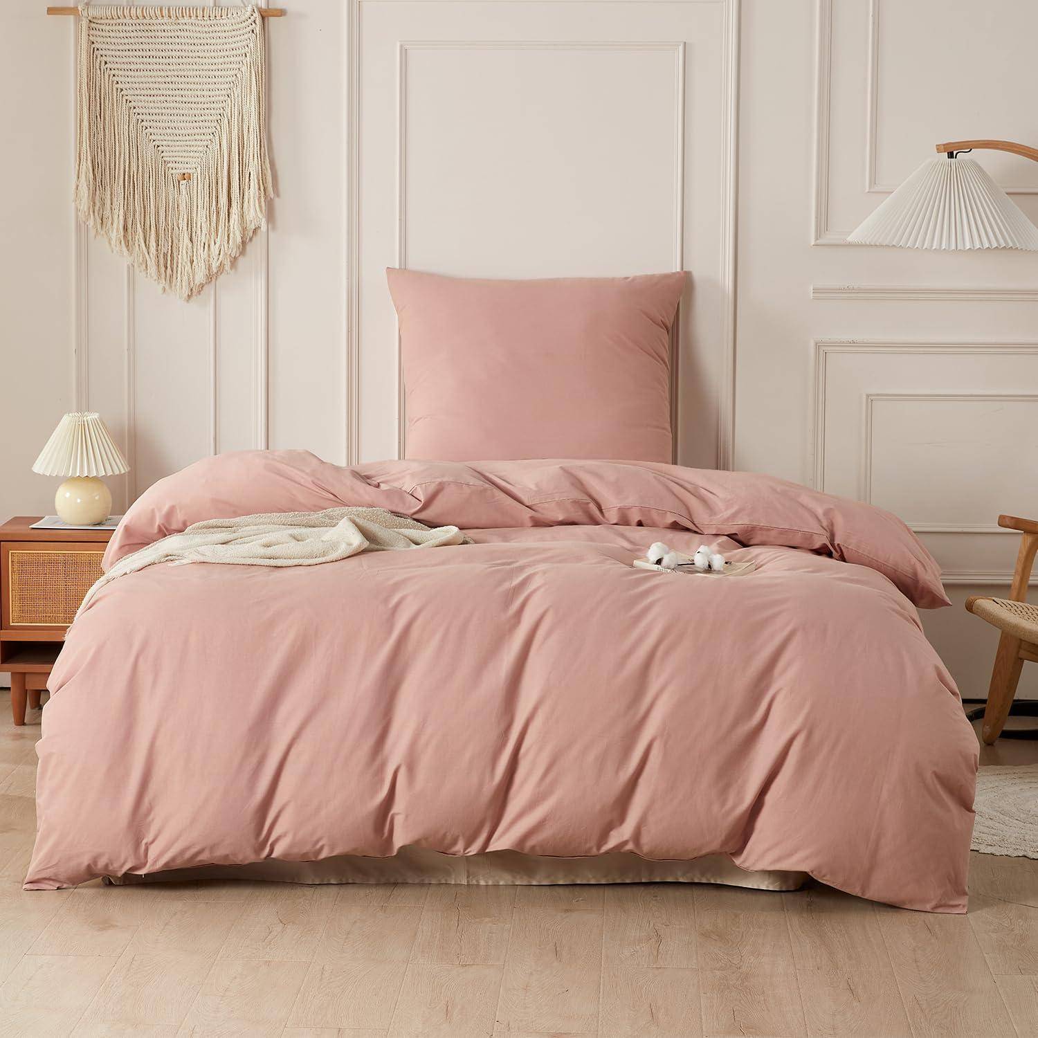 Rosabett mit passendem Kissen und Bettdecke in einem minimalistischen Schlafzimmer, neben einem Holznachttisch und Wanddekoration.