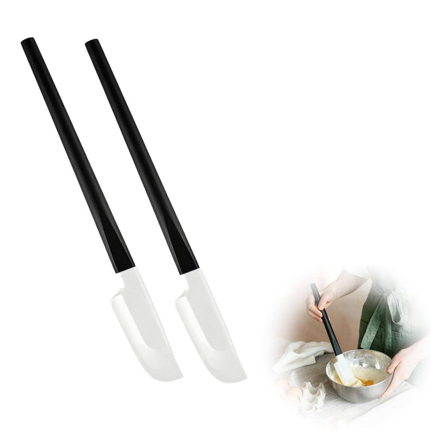 Paar schwarze Silikonspatel mit weißen Köpfen, dargestellt als Produktbild mit einem kleinen Einsatz, in dem jemand Teig in einer Schüssel mischt.