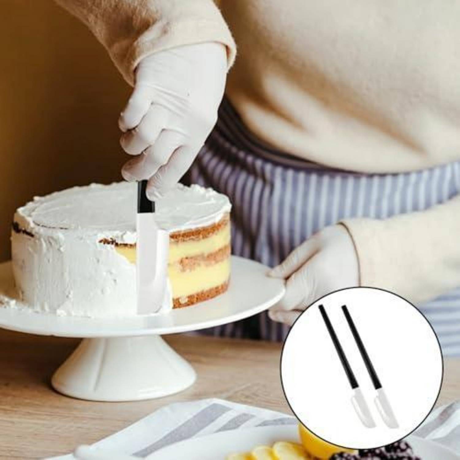 Handschuhe tragende Hände schneiden eine gefrostete Schichttorte auf einem Ständer mit einem Messer; die Einfügung zeigt das Schwarz-Weiß-Musterdesign des Messergrifts.