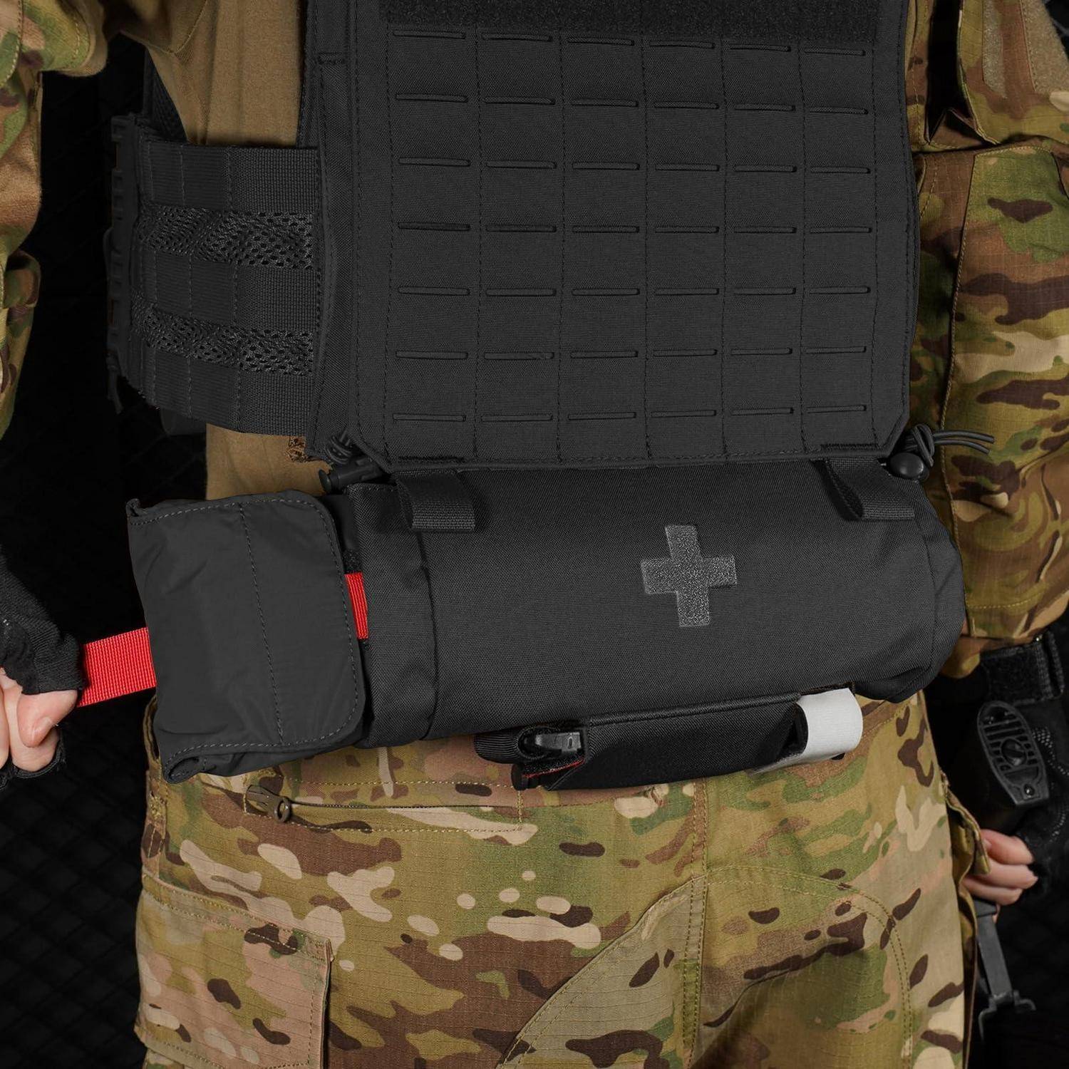 Nahaufnahme einer Person, die Camouflage-Kleidung und eine schwarze taktische Weste mit einem medizinischen Beutel mit Kreuzmarkierung trägt.