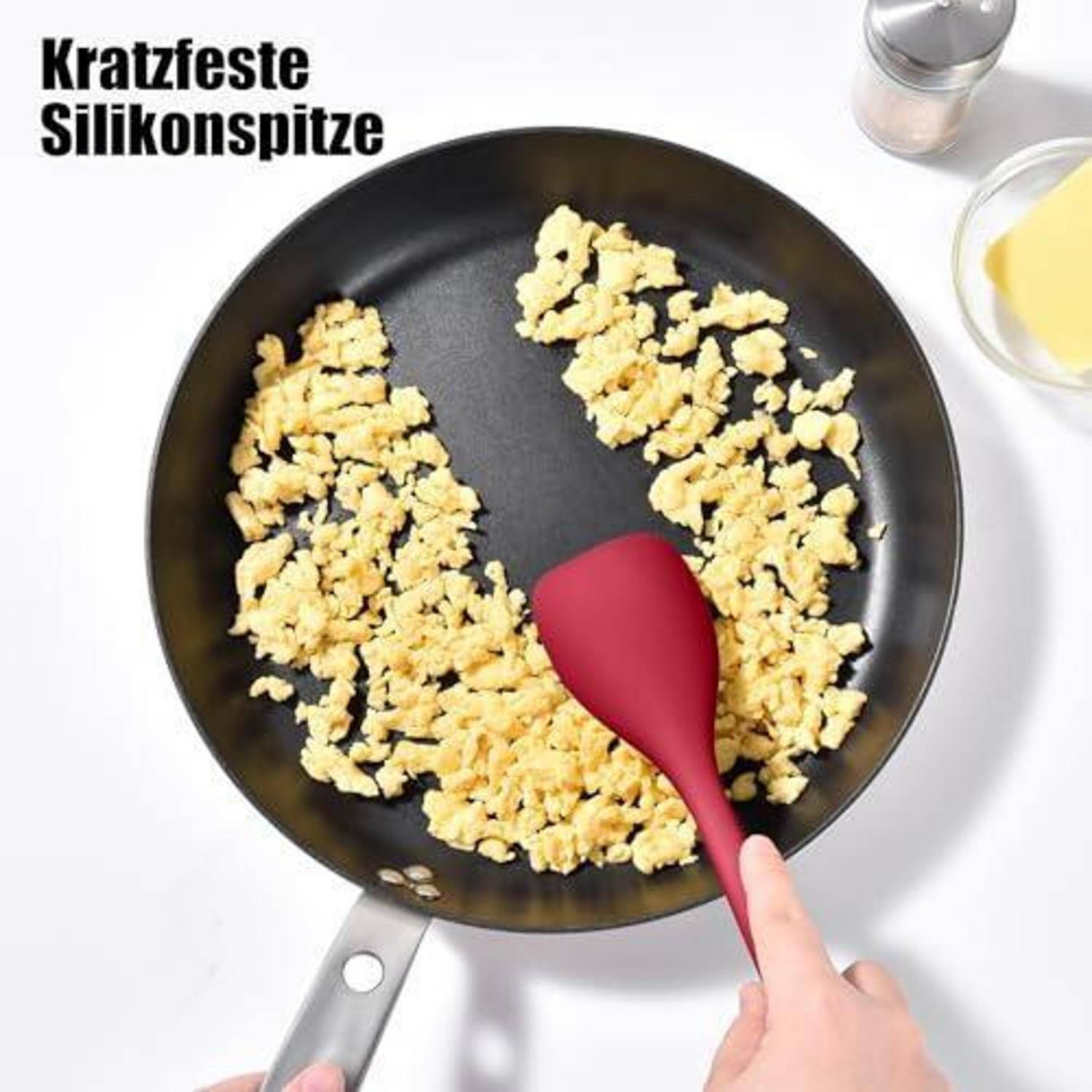 Ein roter Silikonspatel rührt Rühreier in einer schwarzen Pfanne um und zeigt dabei eine kratzfeste Silikonspitze.