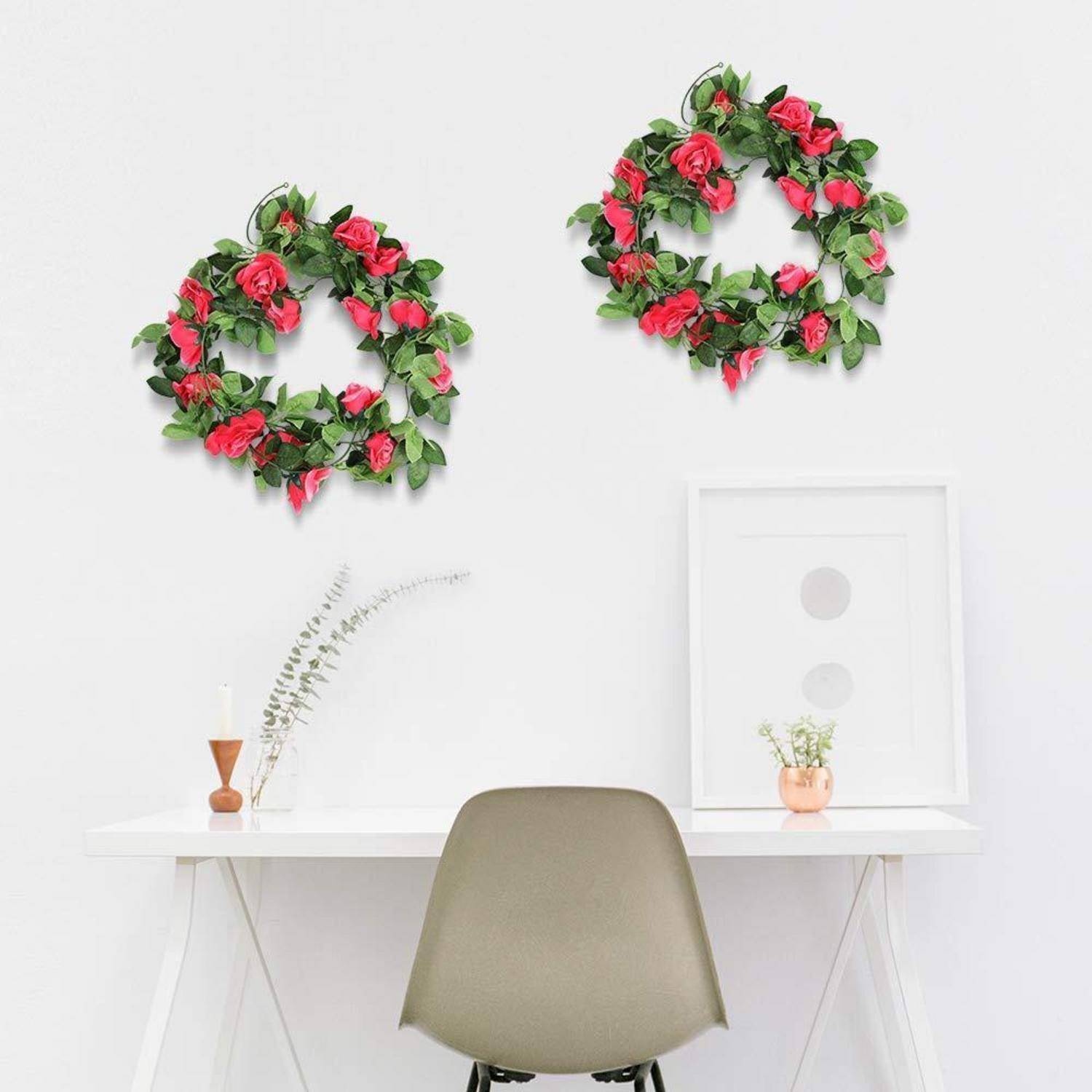 Minimale weiße Büronische mit zwei floralen Kränzen an der Wand über einem Schreibtisch und Stuhl, dekoriert mit schlichten Vasen und gerahmter Kunst.
