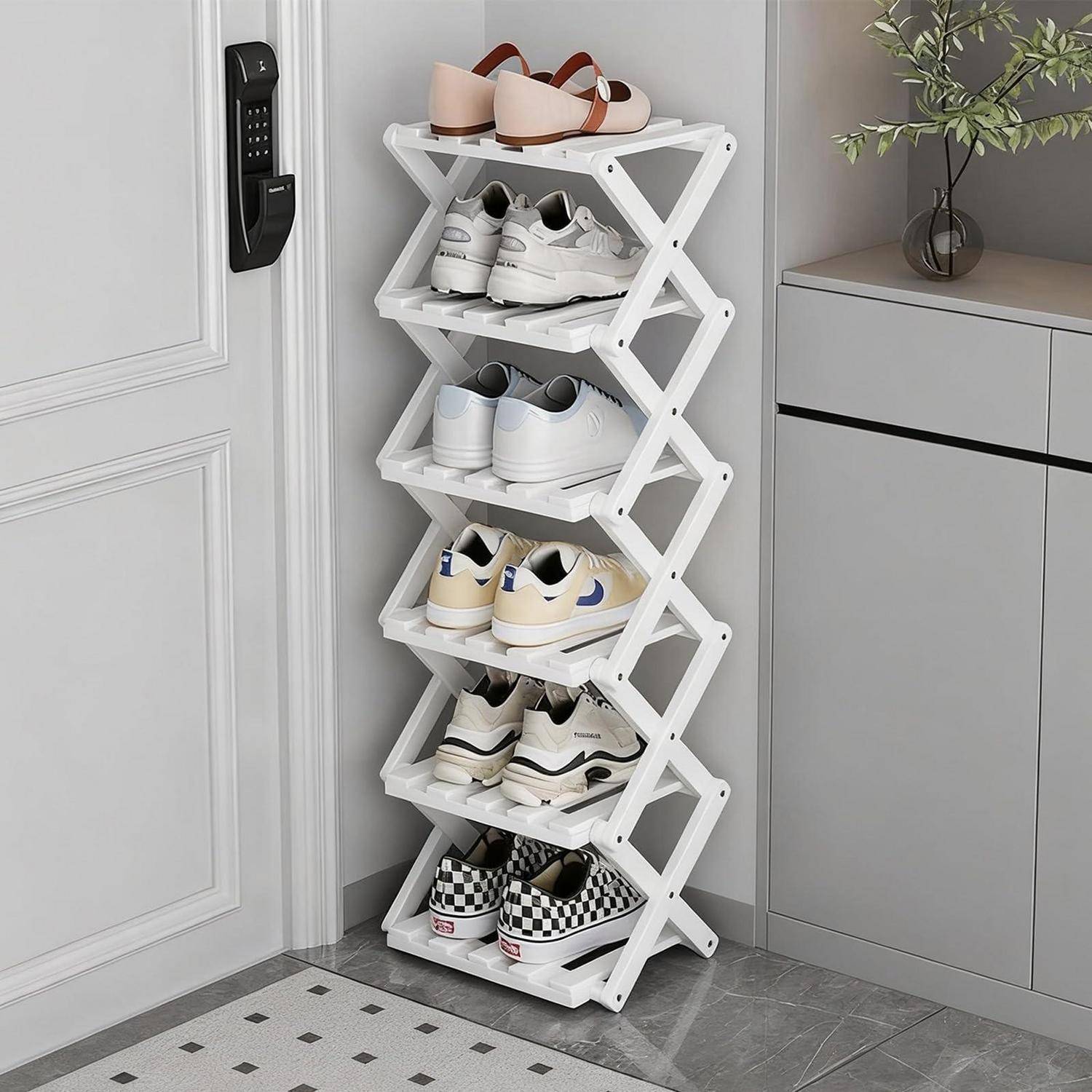 Weißes zusammenklappbares Schuhregal neben einer Tür und einem Schrank, das mehrere Paar Sneaker und Sandalen in einem ordentlichen Eingangsbereich hält.