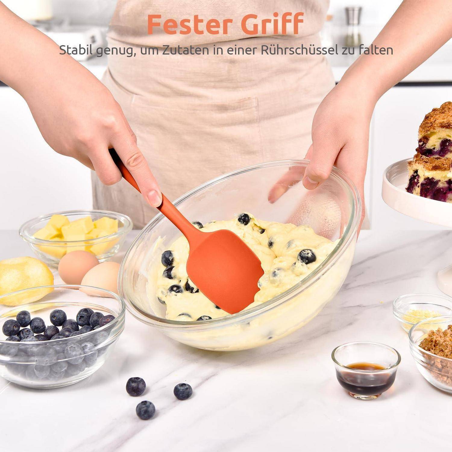 Person rührt Blaubeerkuchen in einer Glasschüssel mit einem orangefarbenen Spatel um; deutscher Text lautet „Fester Griff