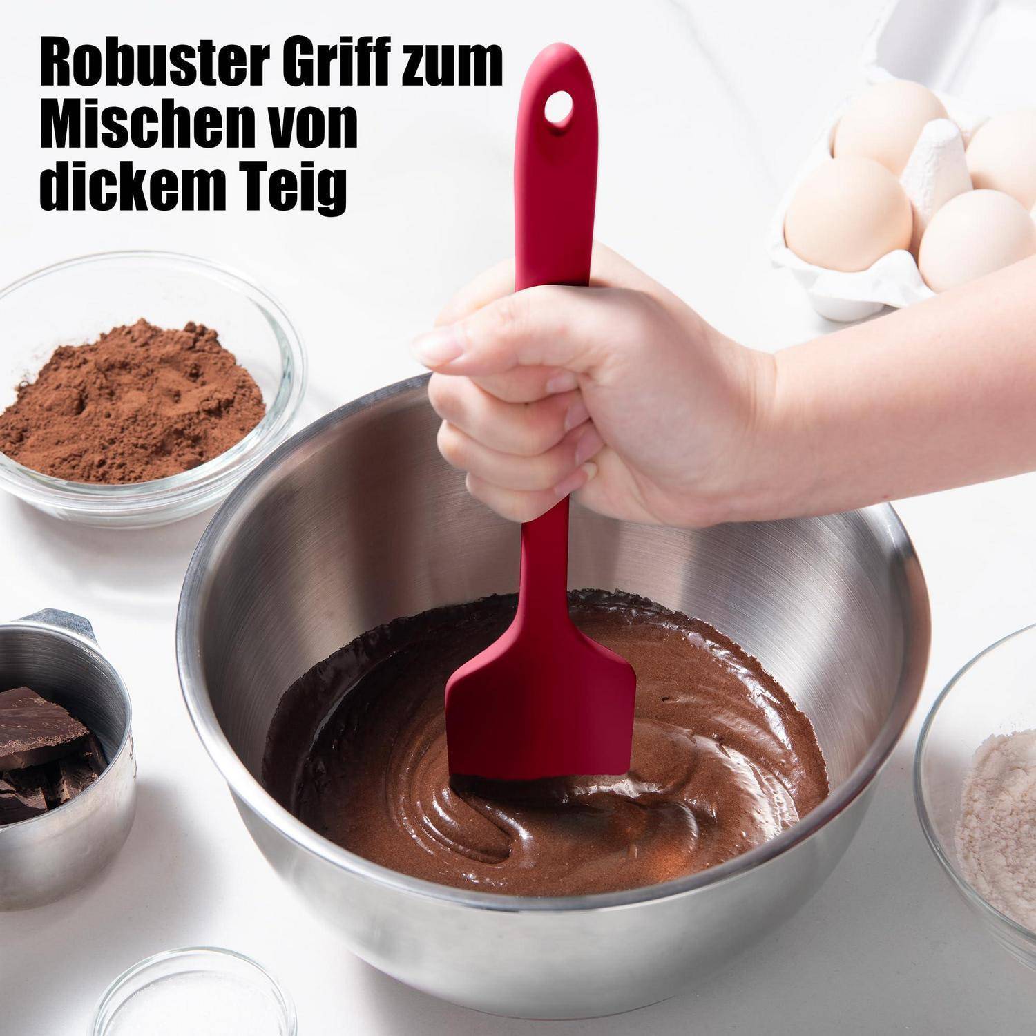 Eine Hand, die einen roten Spatel zum Mischen von dickem Schokoladeteig in einer Metallschüssel verwendet; Deutscher Text sagt „Robuster Griff zum Mischen von dickem Teig