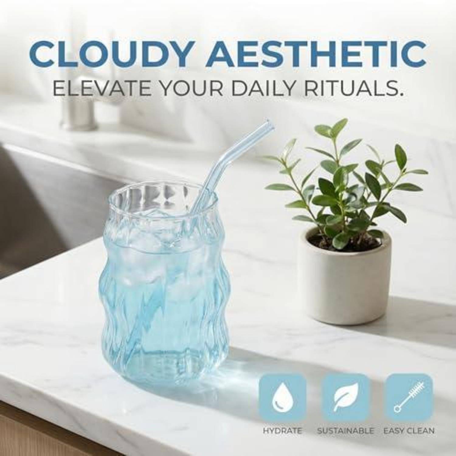 Ein blaues welliges Glas mit einem Strohhalm sitzt auf einer weißen Arbeitsplatte neben einer Topfpflanze; der Text lautet „CLOUDY AESTHETIC" und „ELEVATE YOUR DAILY RITUALS"".