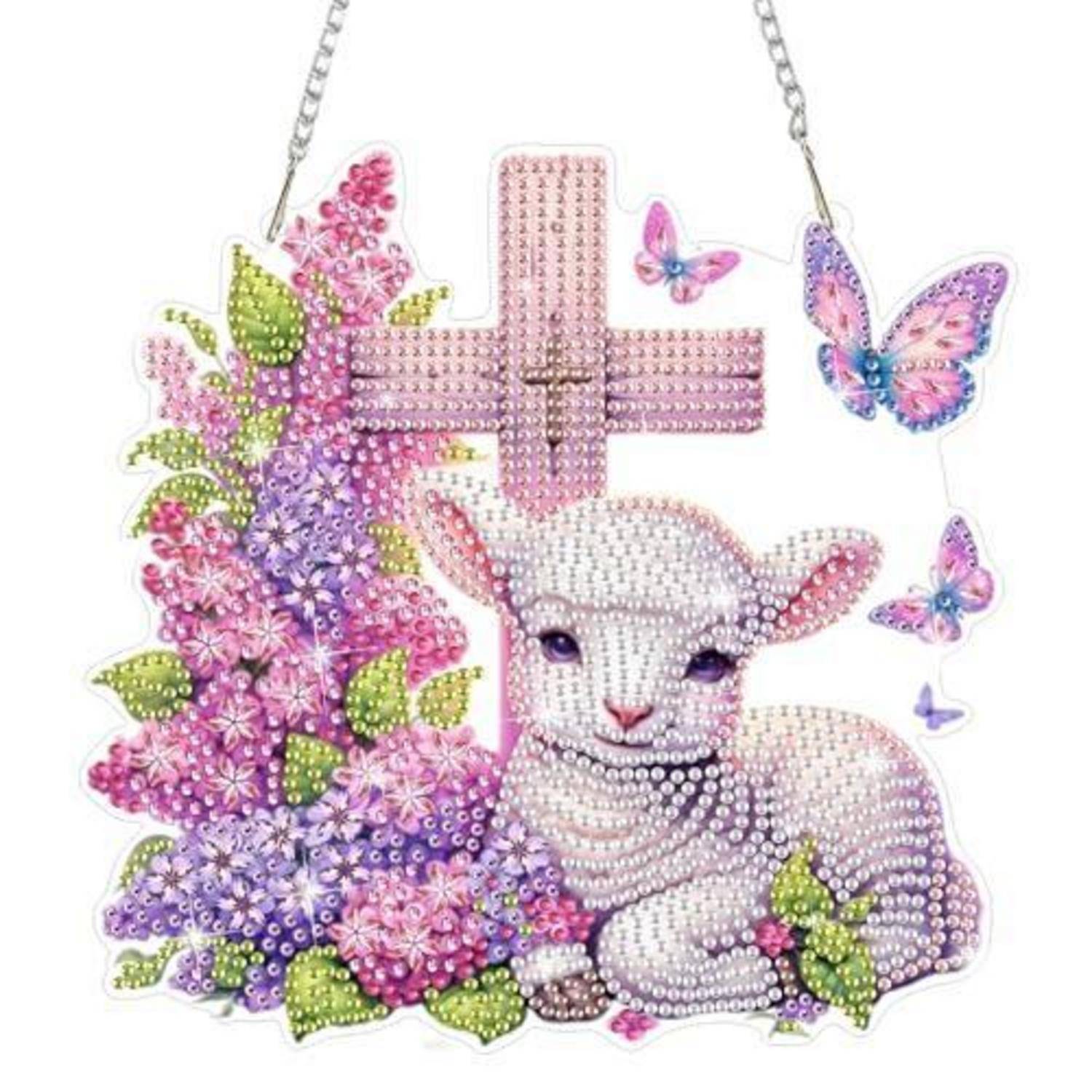 Diamantmalerei eines weißen Lamms neben rosa Blumen und Schmetterlingen, mit einem rosa Kreuz oben, aufgehängt an einer Kette.