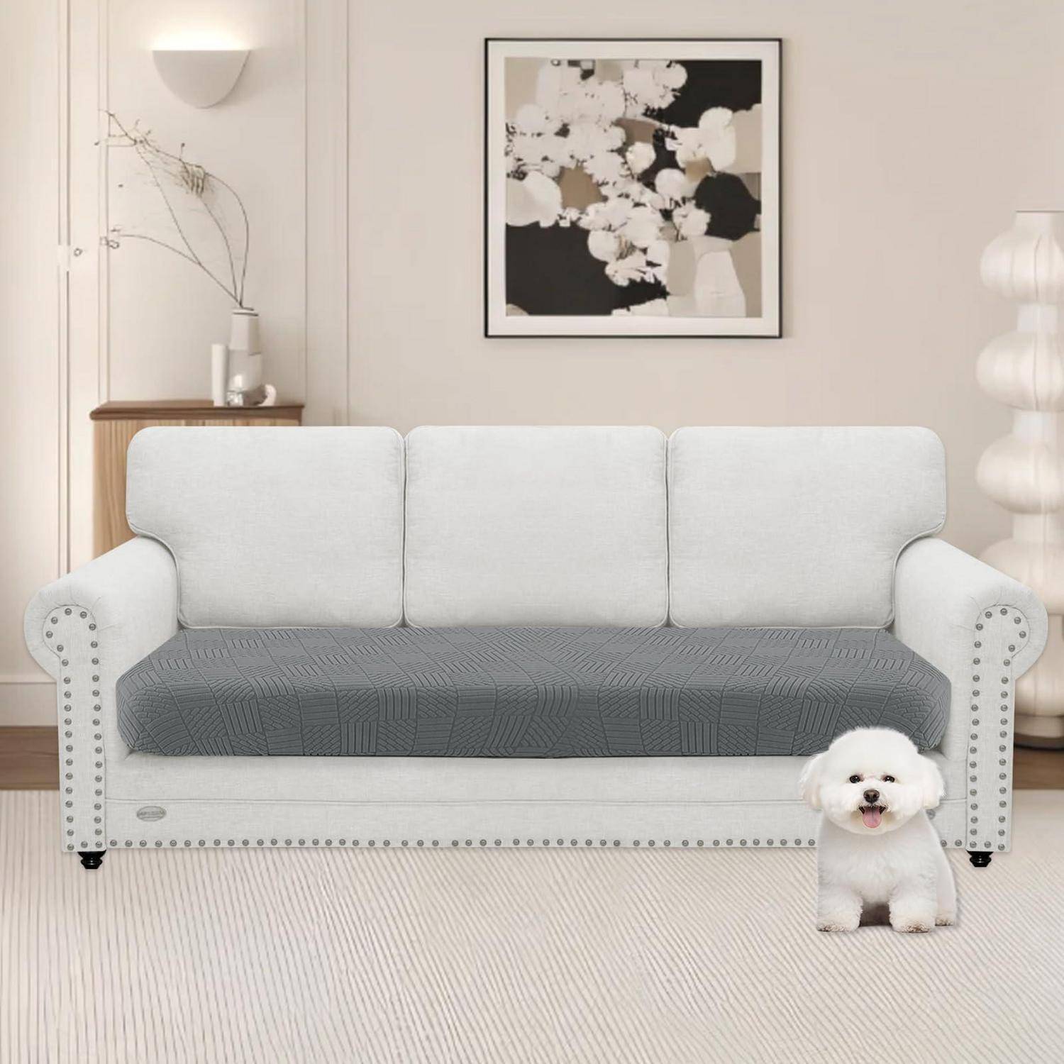 Weißes Sofa mit grauem Sitzbezug in einem minimalistischen Wohnzimmer; ein kleiner weißer Hund sitzt auf dem Boden davor.