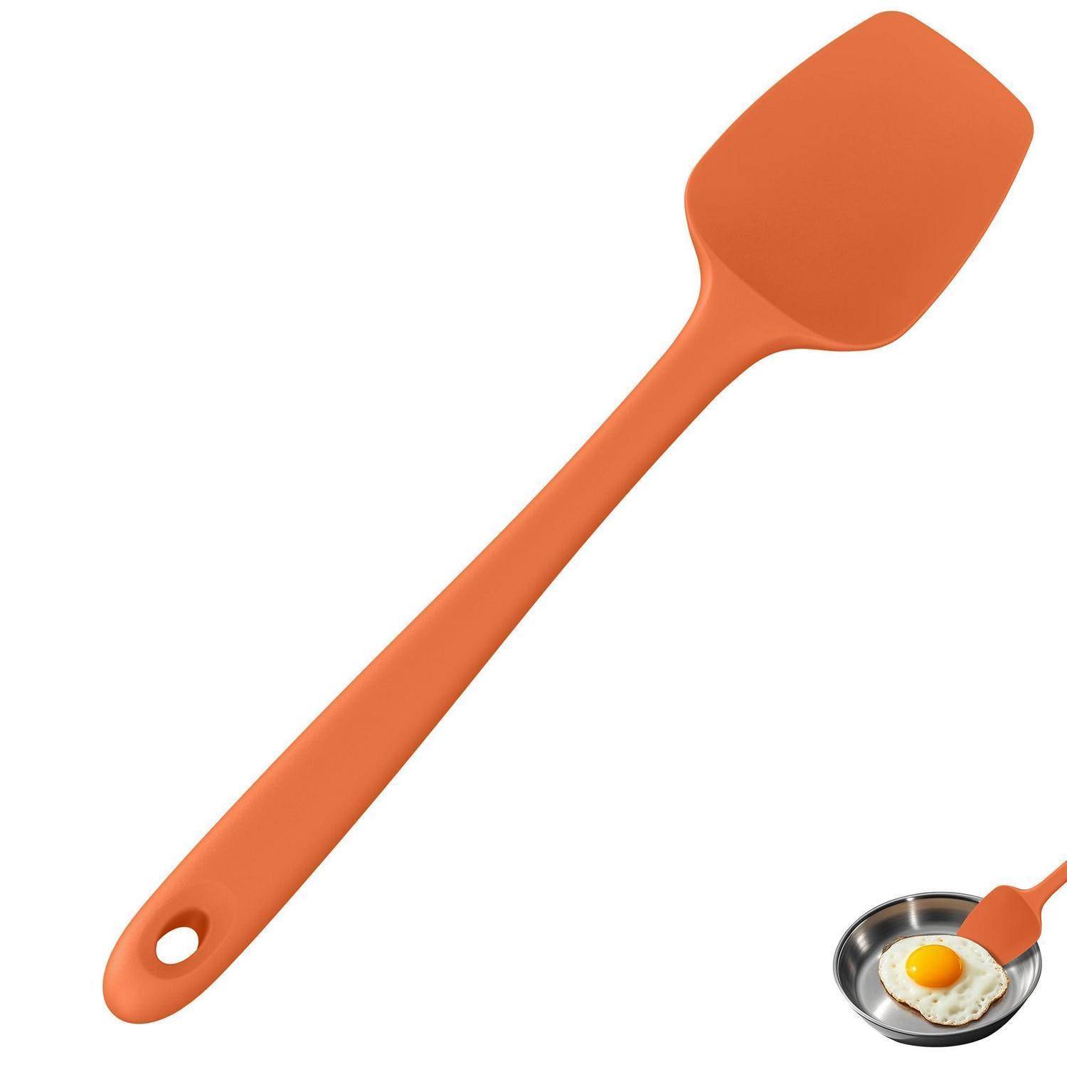 Orangespatel aus Silikon mit Aufhängeloch, gezeigt mit einer kleinen Bratpfanne, die in der Ecke ein Spiegelei hält.