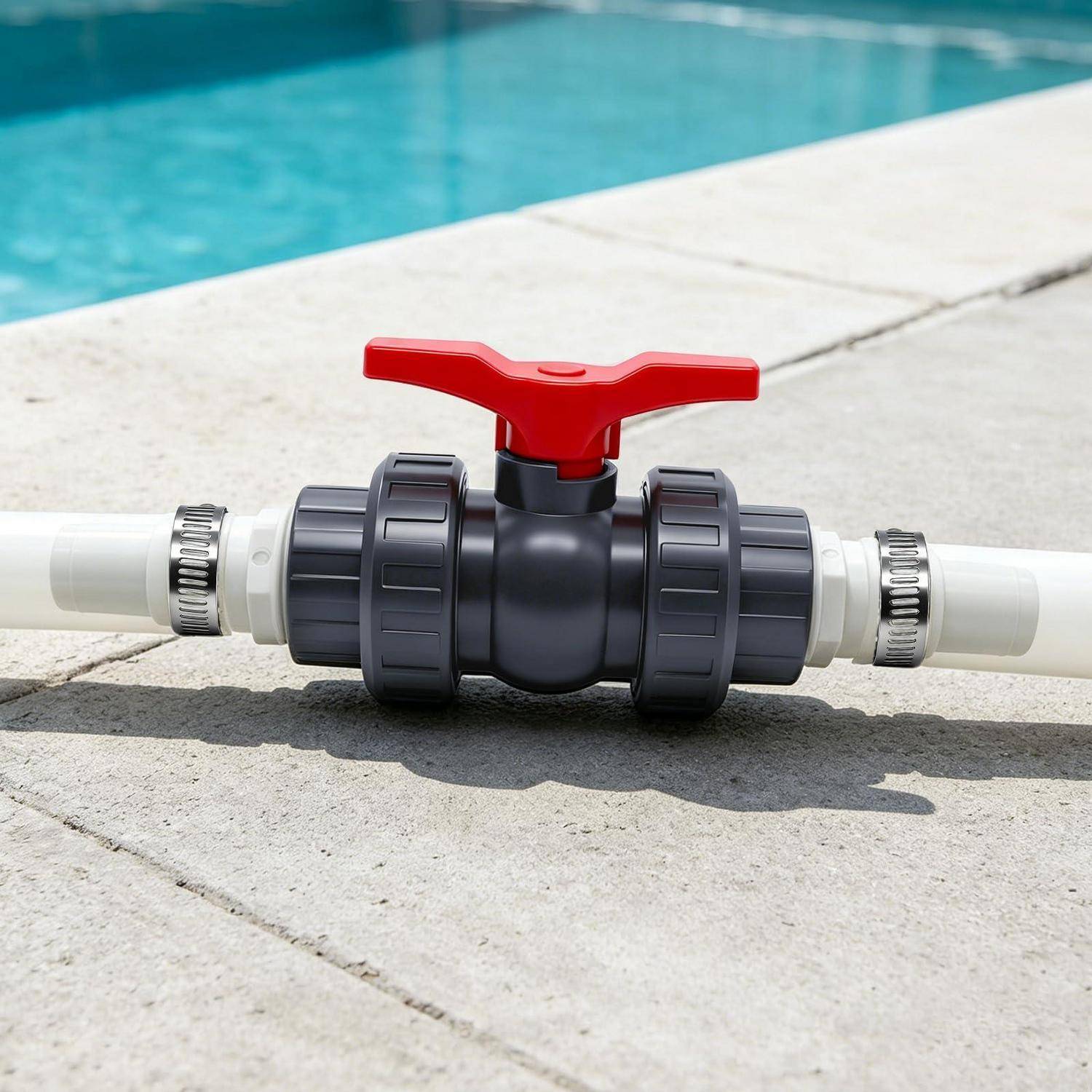 Rotes Absperrventil für den Pool, das mit einem weißen PVC-Rohr neben einem Schwimmbecken verbunden ist.