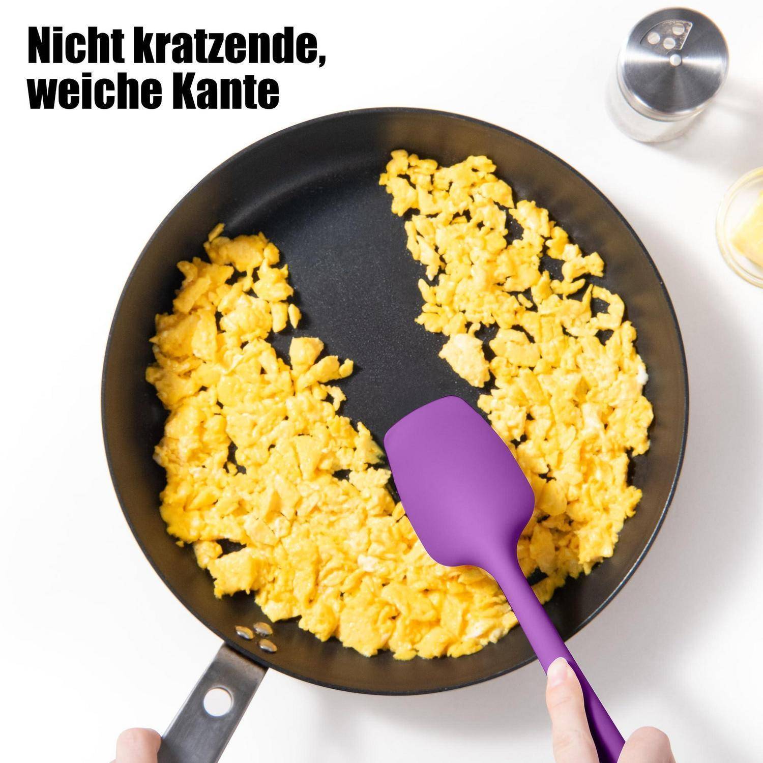 Bratpfanne mit Rühreiern und einem violetten Spatel, der den deutschen Text 