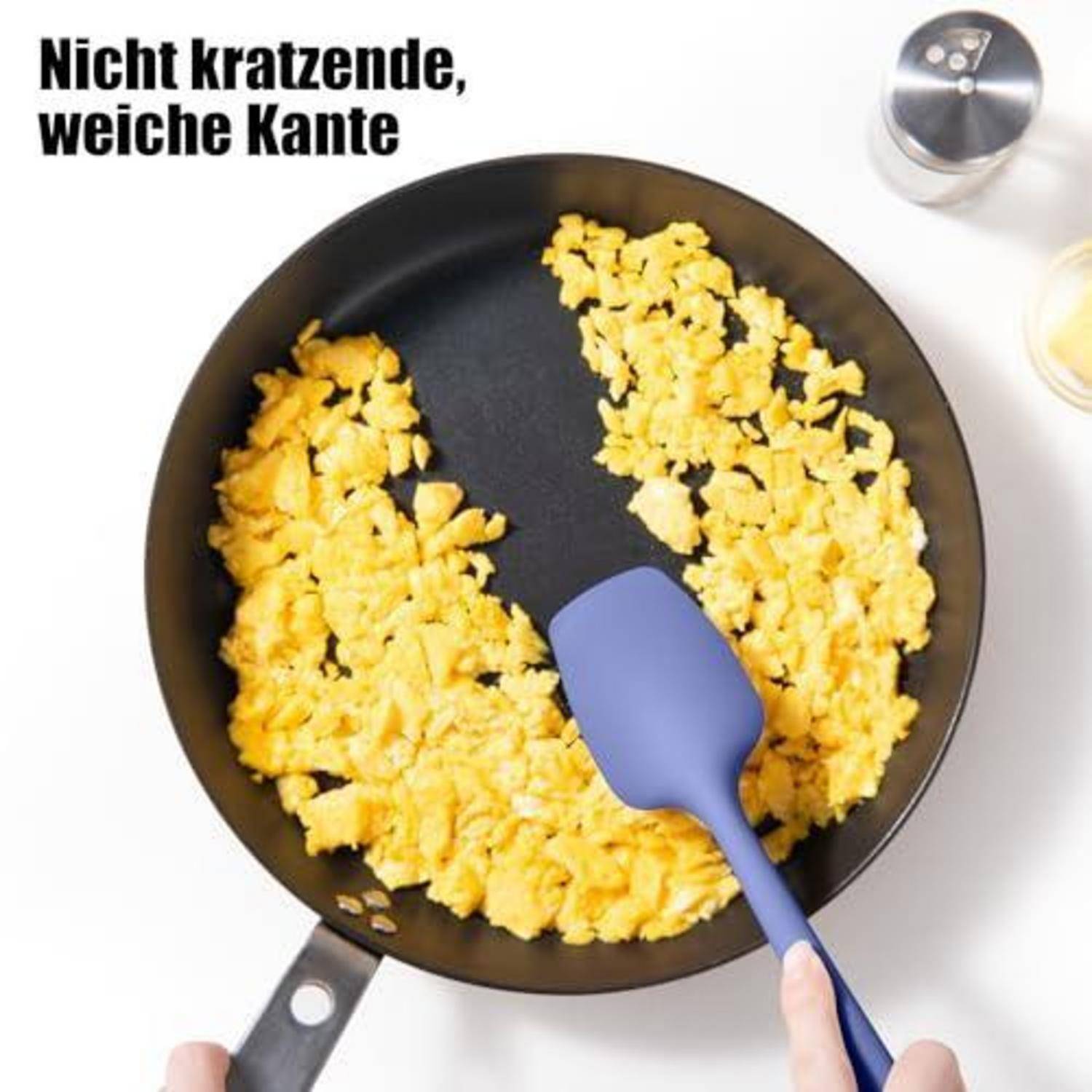 Draufsicht auf Rührei in einer Pfanne, das mit einem Spatel gerührt wird, mit deutschem Text 
