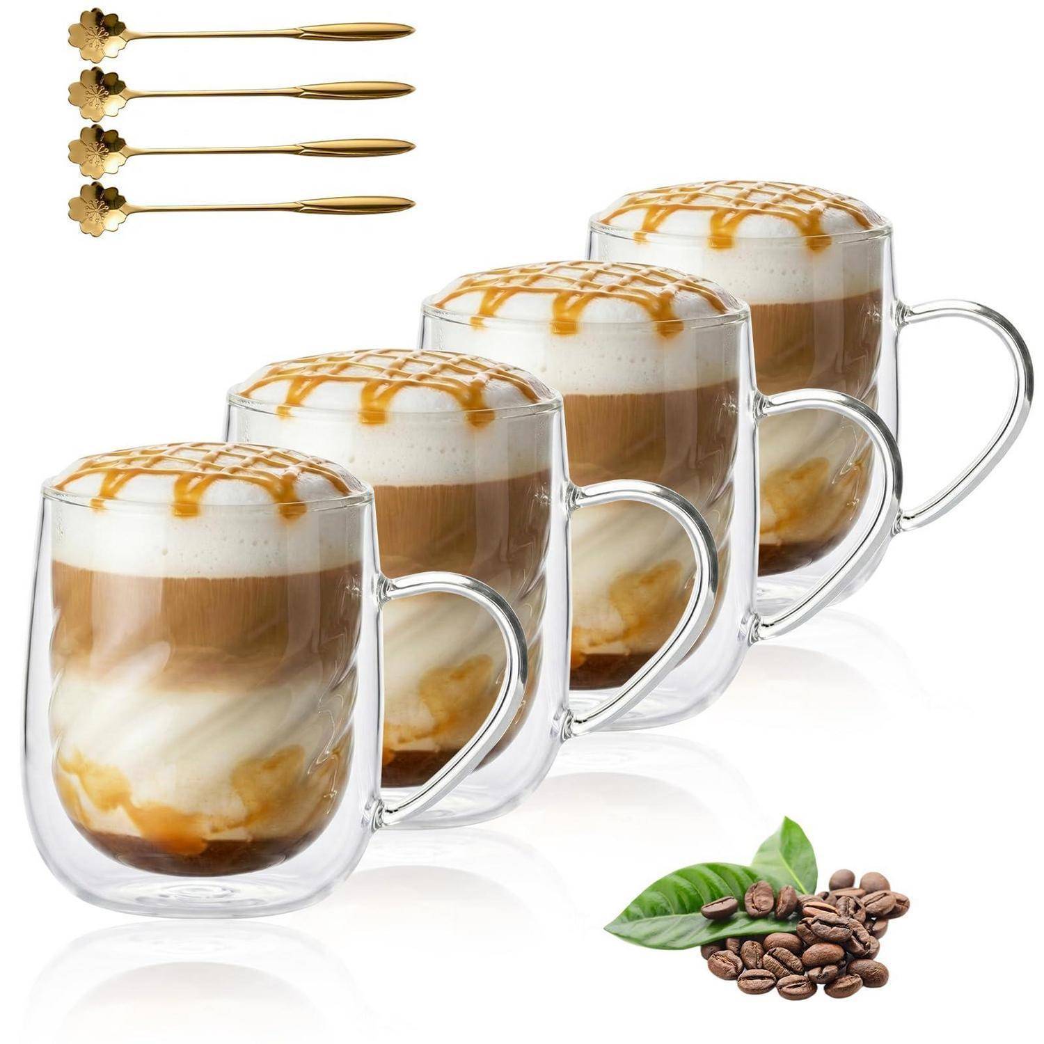 Vier geschichtete Kaffegetränke in klaren doppelwandigen Bechern mit Karamellsirup, plus dekorative Kaffeebohnen und goldene Löffel.