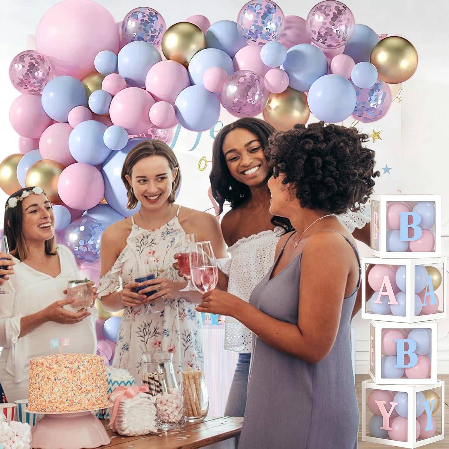 Frauen stoßen bei einer Babyparty mit Getränken unter einem pastellfarbenen Ballonbogen an, mit stapelbaren Blöcken, die neben dem Desserttisch "BABY"" buchstabieren.