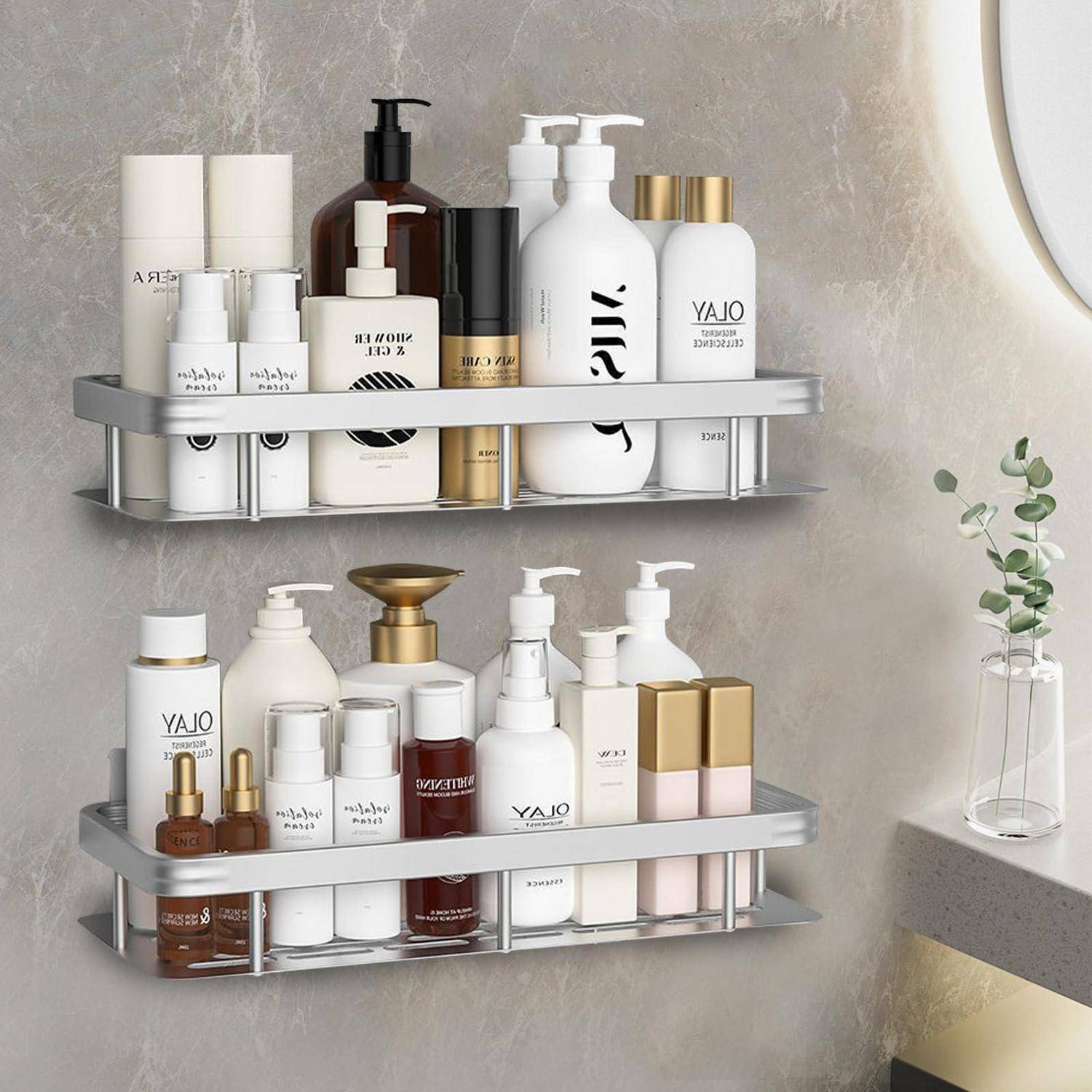 Zwei an der Wand montierte silberne Regale halten verschiedene Hautpflege- und Toilettenartikel in weißen und goldenen Flaschen und Gläsern, die in einem Badezimmer angeordnet sind.