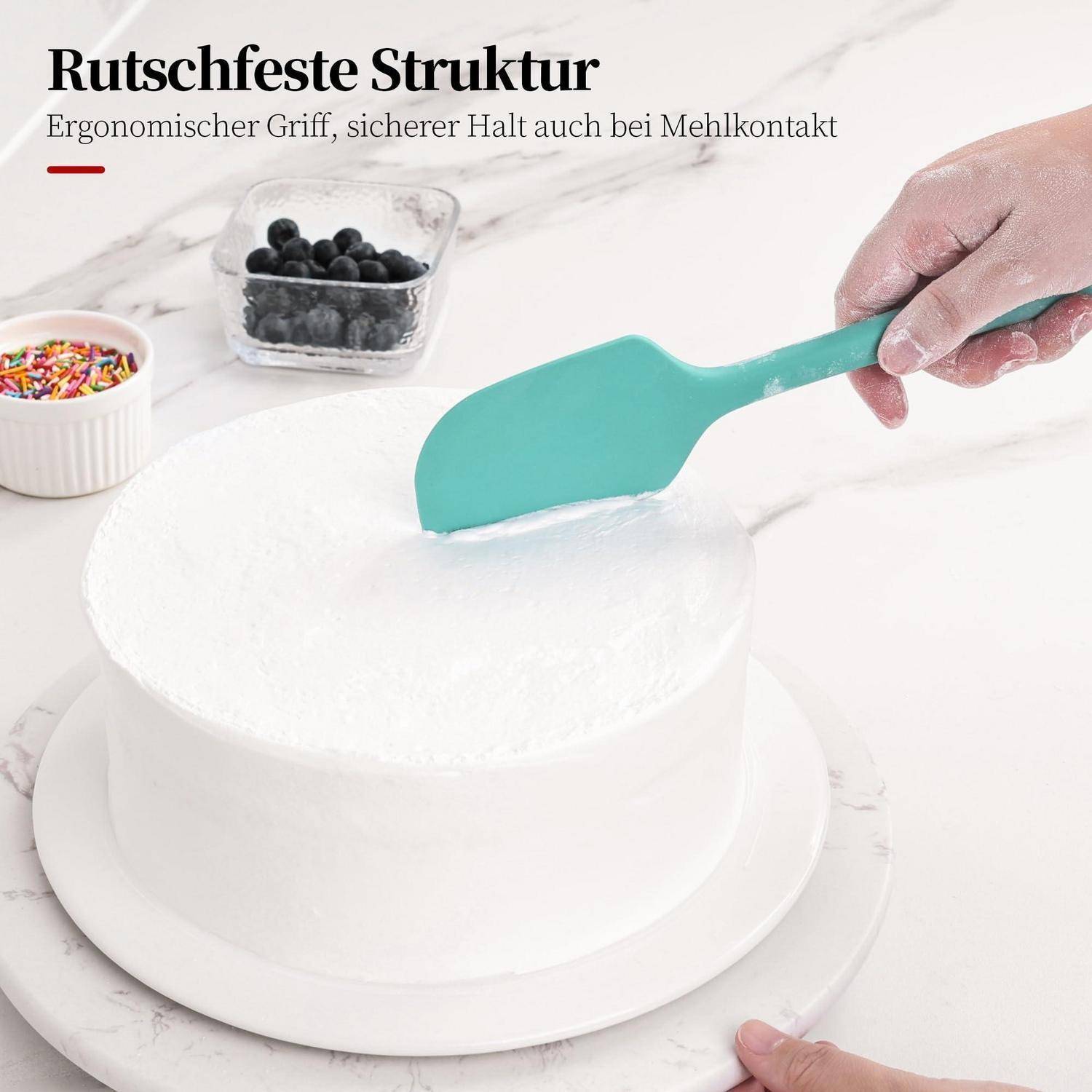 Hand hält einen türkisfarbenen Spatel mit rutschfestem Griff und glättet weiße Glasur auf einem runden Kuchen; deutscher Text sagt „Rutschfeste Struktur