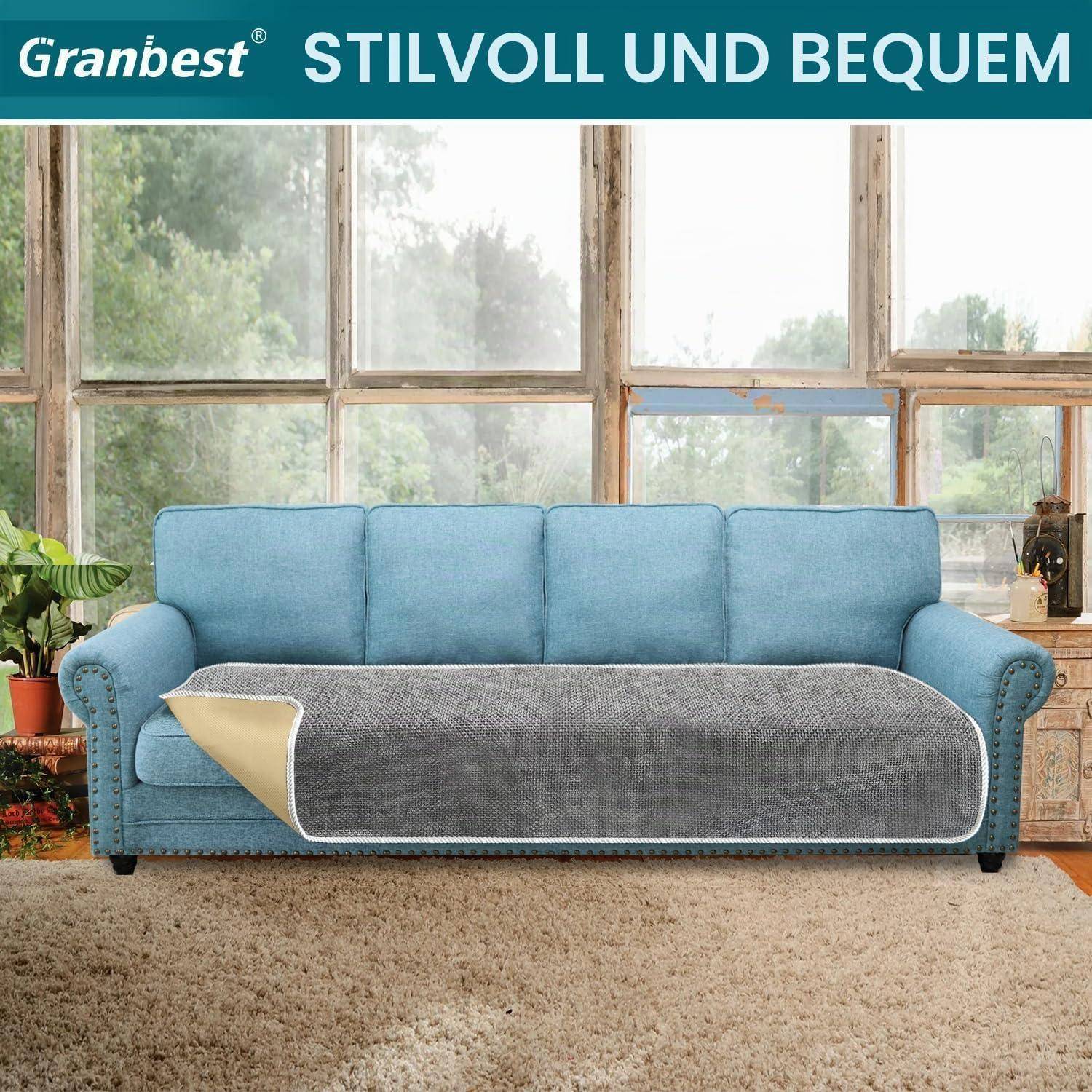 Blaues Sofa mit einer grauen Wurfdecke in einem hellen Wohnzimmer, mit den Texten „Granbest" und „STILVOLL UND BEQUEM"" oben.
