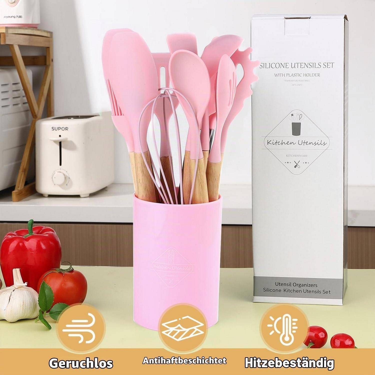 Rosa Silikon-Küchenutensilien-Set in einem rosa Behälter neben seiner Schachtel, mit Etiketten für geruchlos, antihaftbeschichtet und hitzebeständig.
