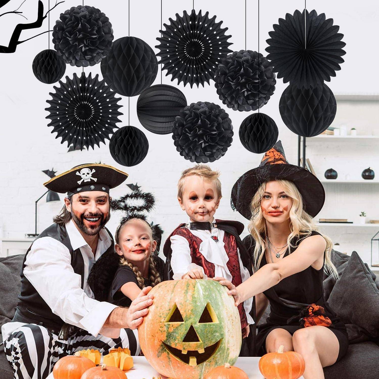 Familie in Piraten- und Hexenkostümen posiert mit zwei Kindern um einen geschnitzten Kürbis herum zu einer Halloween-Feier.