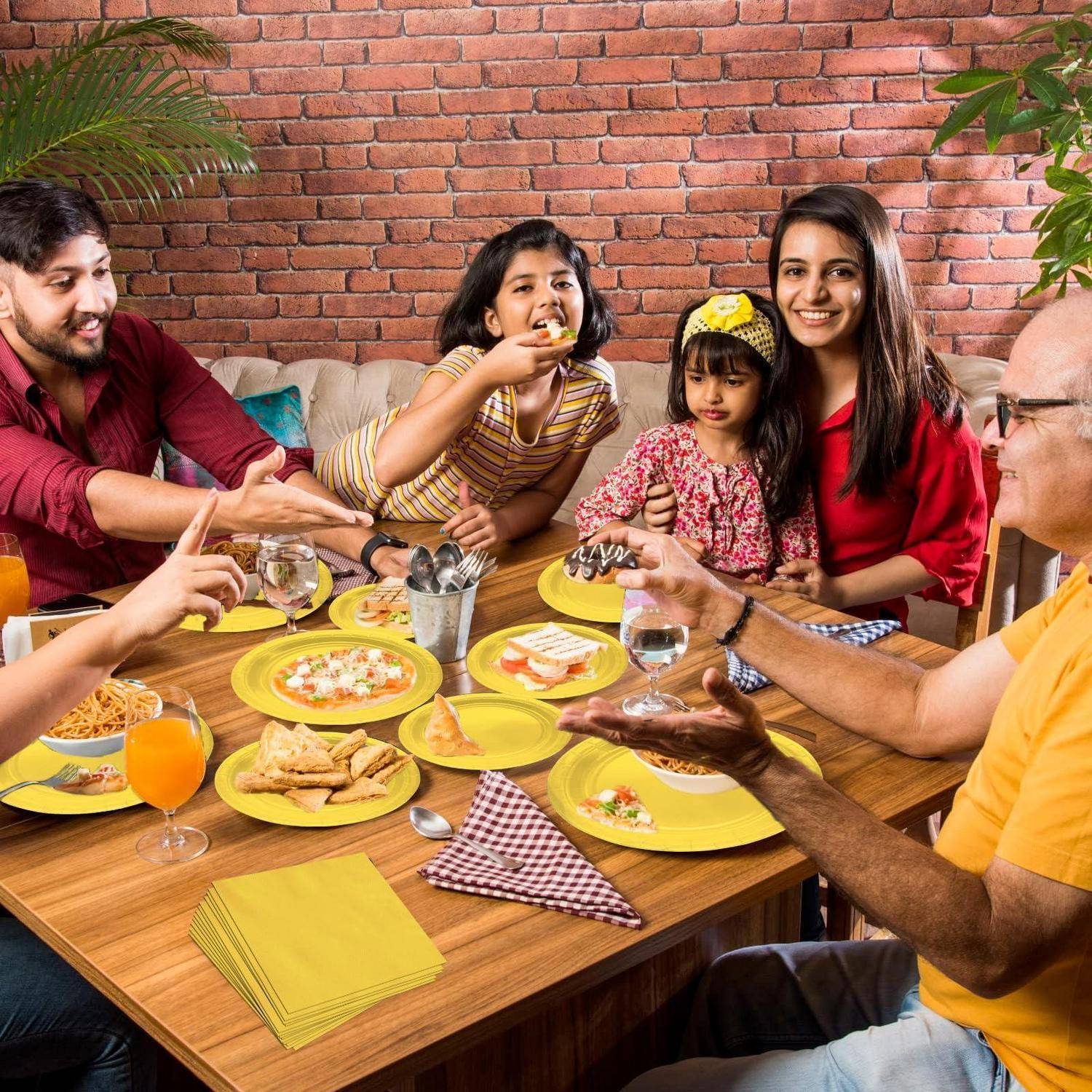 Familie und Freunde teilen eine Mahlzeit um einen Tisch, lachen und reichen sich Essen bei einem ungezwungenen Treffen in einem Restaurant mit Backsteinwänden.