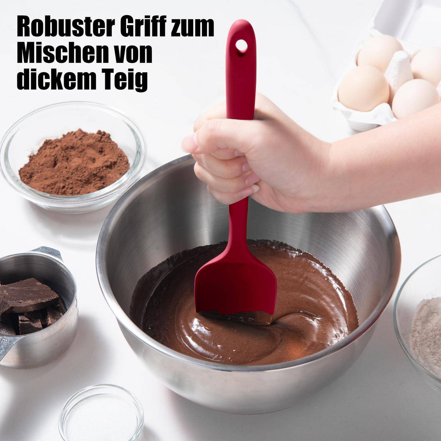 Eine Hand rührt dicken Schokoladeteig in einer Metallschüssel mit einem roten Spatel um; der deutsche Text lautet „Robuster Griff zum Mischen von dickem Teig