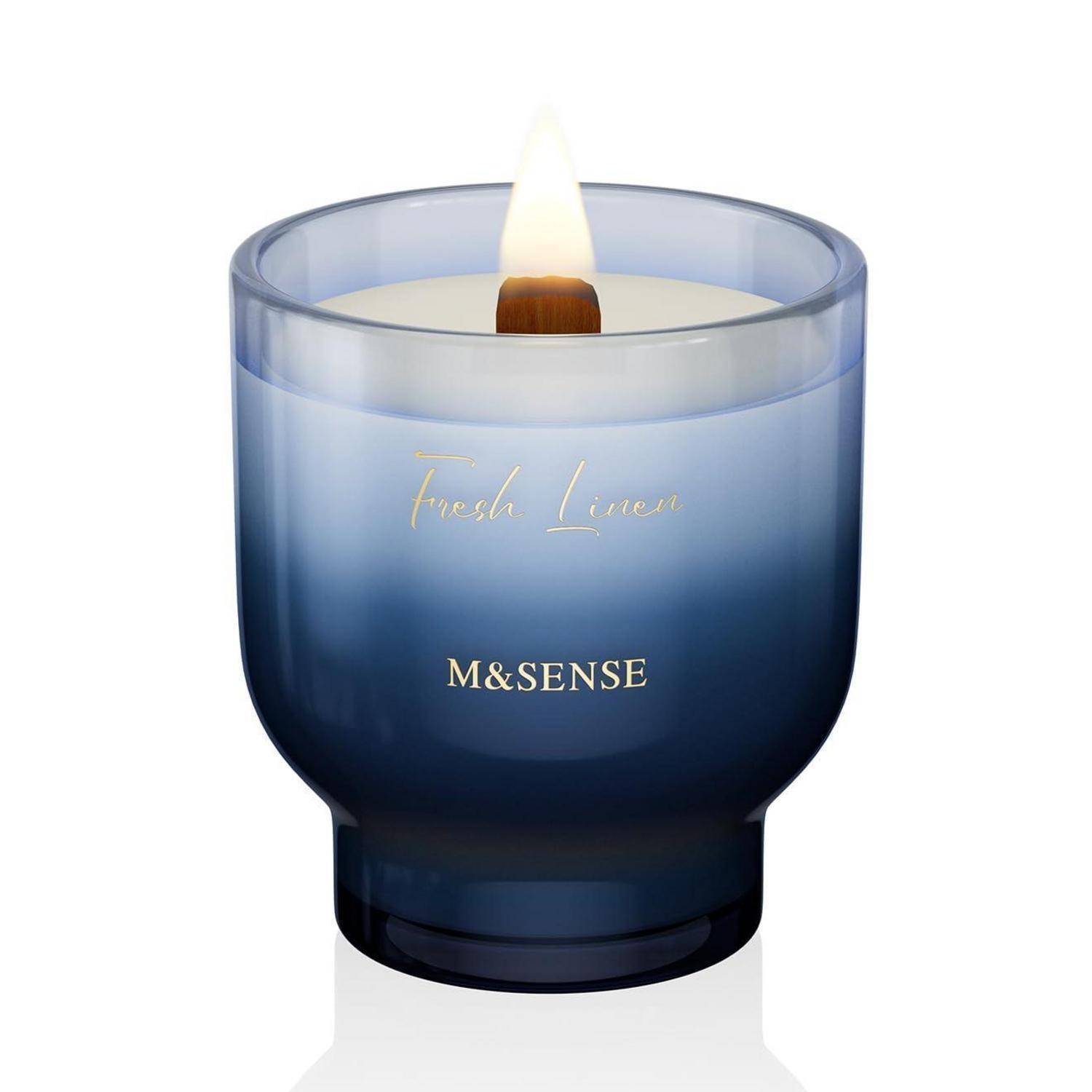 Blaue Glaskerze mit brennendem Docht, beschriftet mit „Fresh Linen