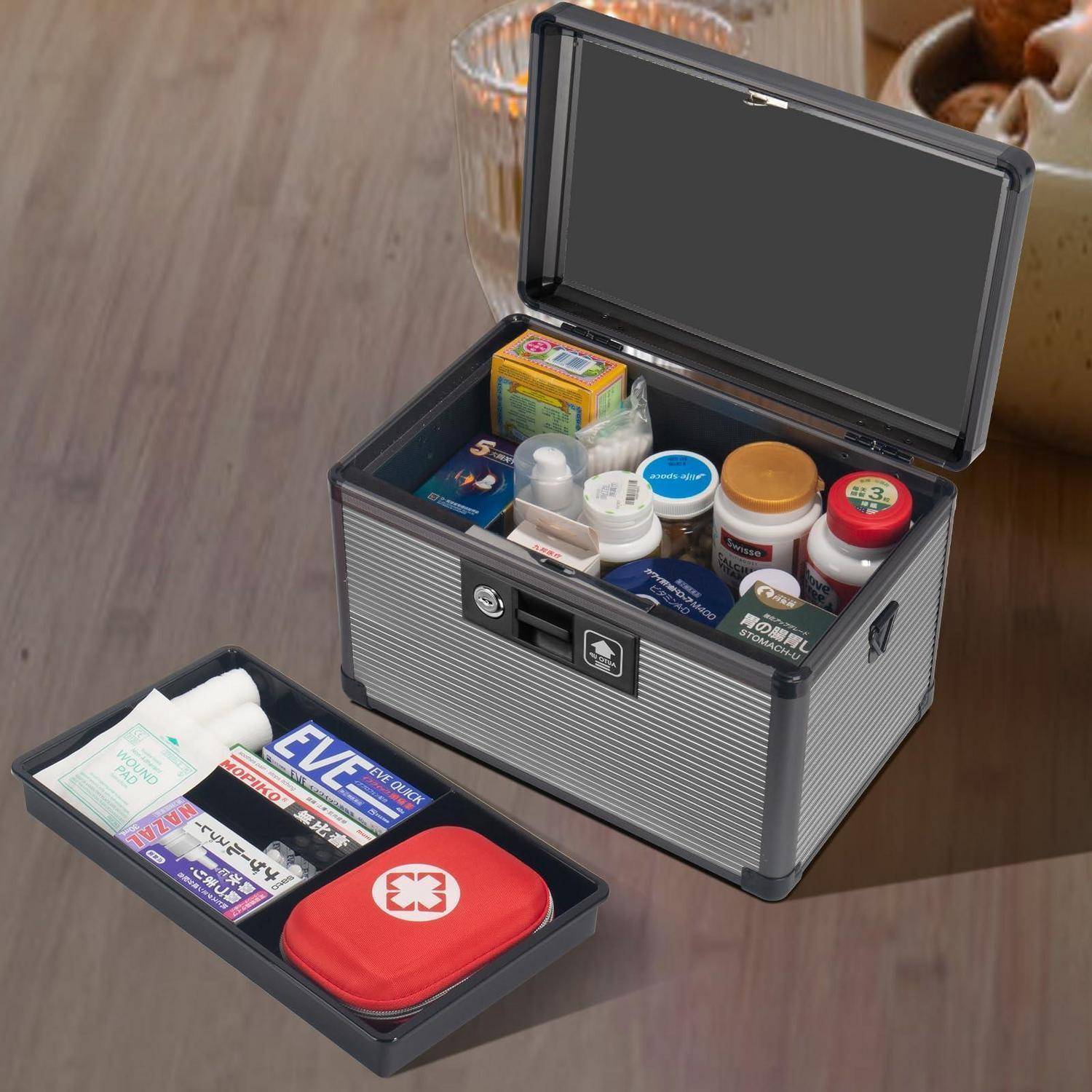 Öffnen Sie die erste-Hilfe-Aufbewahrungsbox mit Medikamenten und Verbandsmaterialien, die in abnehmbaren Tabletts auf einem Holztisch ordentlich organisiert sind.