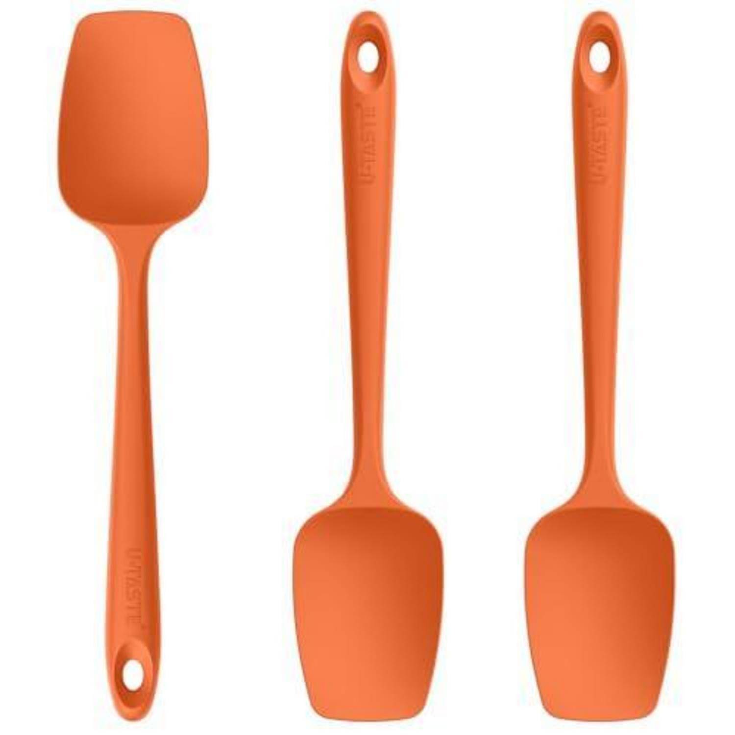 Drei orange Silikonspachteln auf weißem Hintergrund, einschließlich einer Schlitzspachtel und zwei massiven Spachteln.